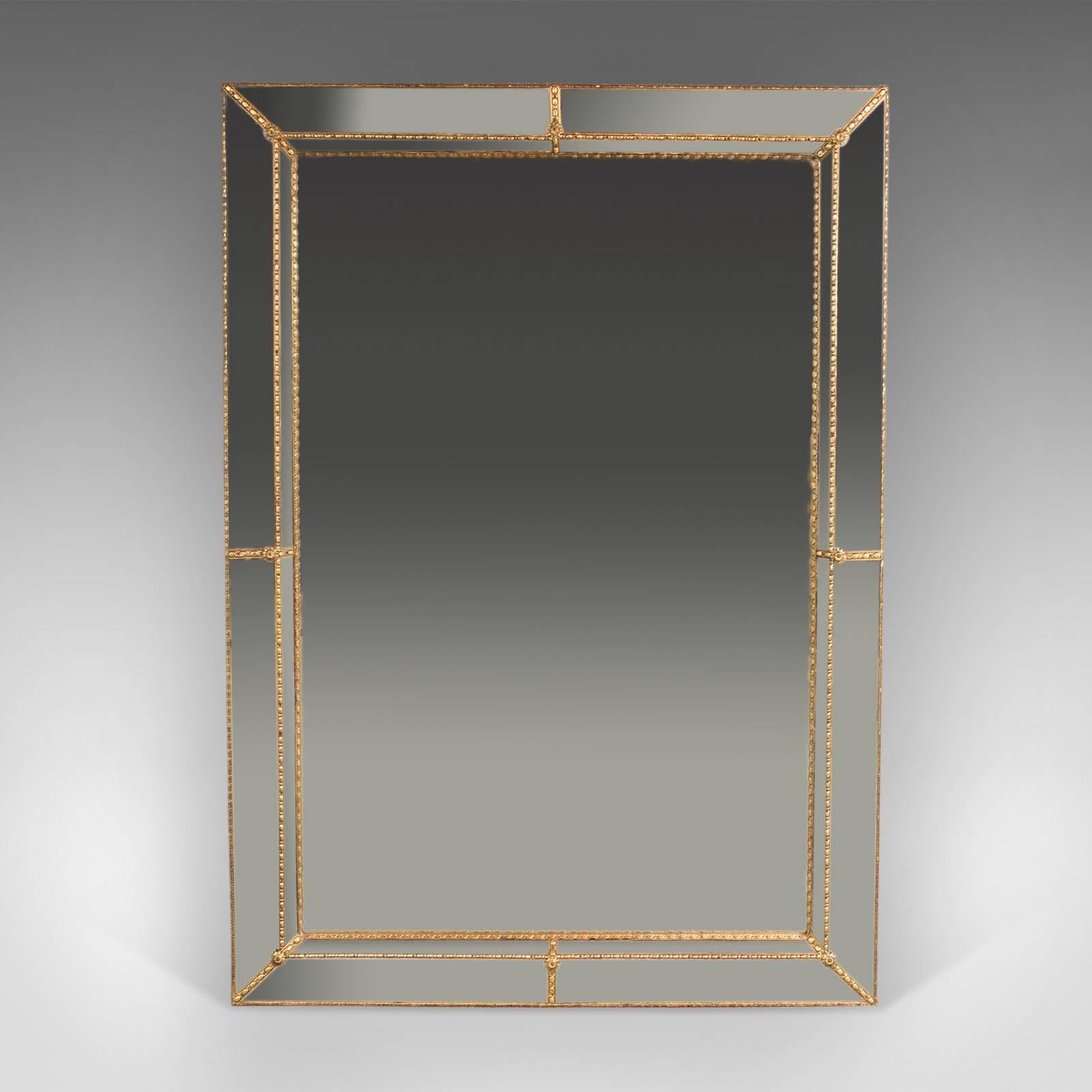 This is a Mid-Century wall mirror, cushioned overmantel or hall mirror.

Beaded gilt frame with rosette details to inner joints
Recessed mirror plate framed by canted rows of mirrored squares
Squares reflecting hints of colored hues

A quality