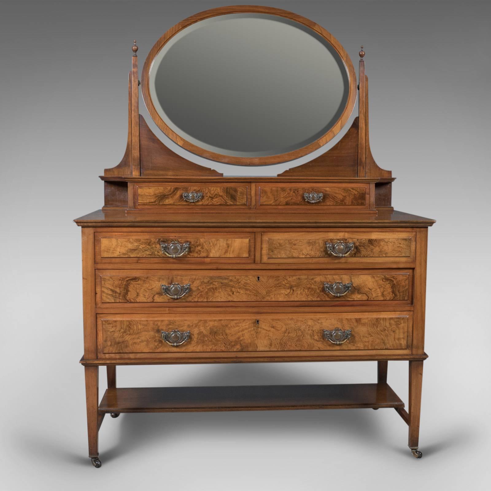 This is a stunning antique dressing table, an Edwardian vanity chest of drawers with an ovular swing mirror, English, circa 1910. Originally made and retailed by Rose & Co. of Stockton-on-Tees.

First class condition in English walnut with a