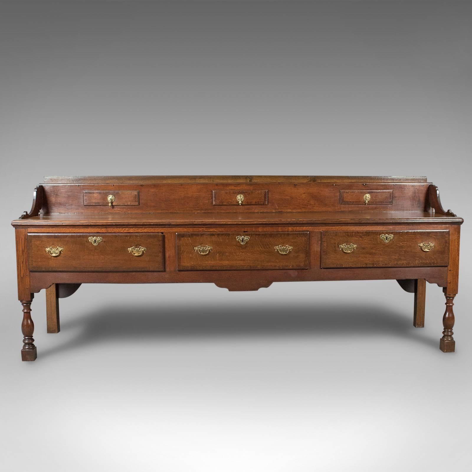This is a large antique dresser base from the early Georgian period, 1750 and later, English in oak.

Of grand, country house, proportions and quality
In English oak displaying wisps of medullary rays
Desirable color in a waxed finish with an