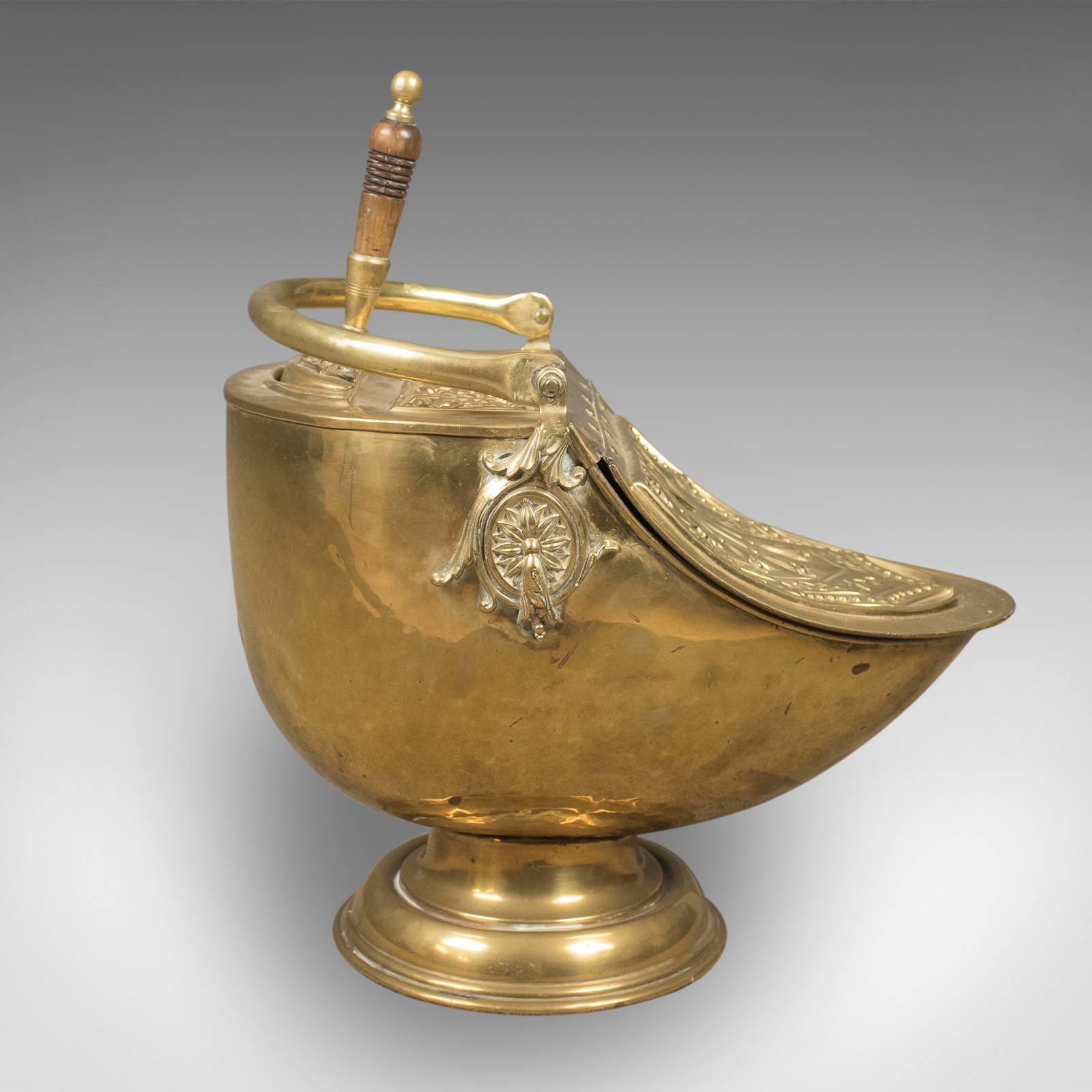 This is a Victorian coal scuttle, a brass fireside piece with integral shovel. English dating to circa 1880.

A pleasing mid-size fireside storage bin presented in good antique condition
Decorated with classical motif and adornment standing upon