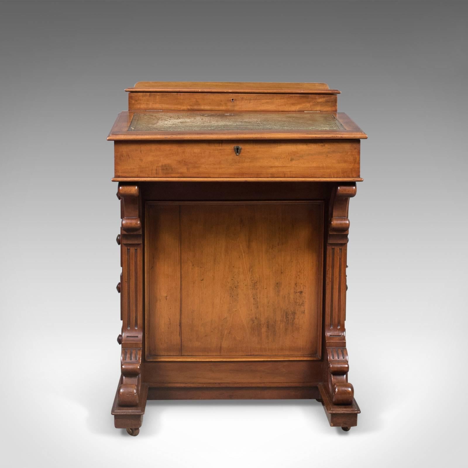 This is an antique Davenport, an English, Victorian writing desk in mahogany dating to circa 1870.

Presented with good colour and a desirable aged patina
Classical brackets and fluting decorating the lower front of the cabinet
Riding upon the