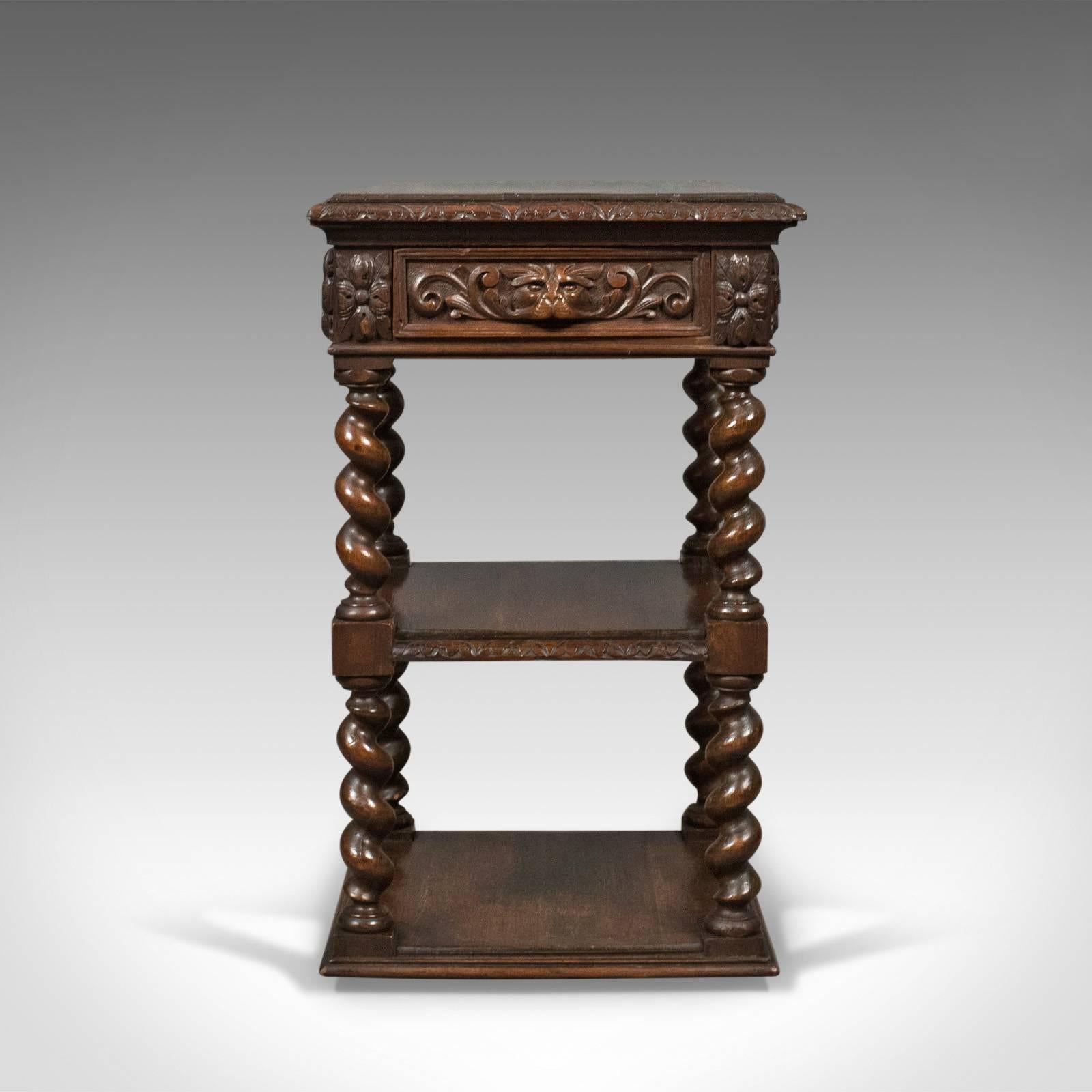 This is an antique side table, a carved green man English oak stand or whatnot dating to circa 1880.

Deep rich color with a desirable aged patina to the English oak
Three tiers raised on unusually stout, barley twist risers
Good proportions and