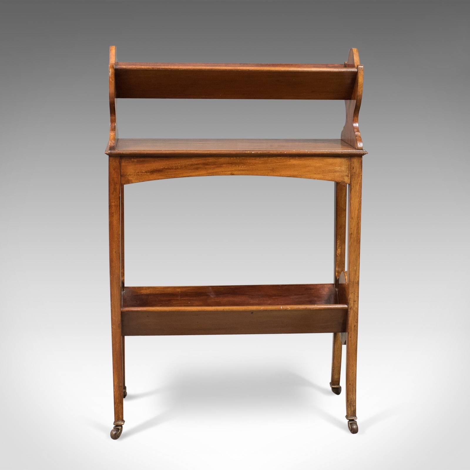 This is an antique bookstand, an English Edwardian mobile book shelf in mahogany dating to circa 1910.

Attractive honey tones and a lustrous finish to the mahogany
Mobile desk companion riding upon original ceramic castors
Offering ample
