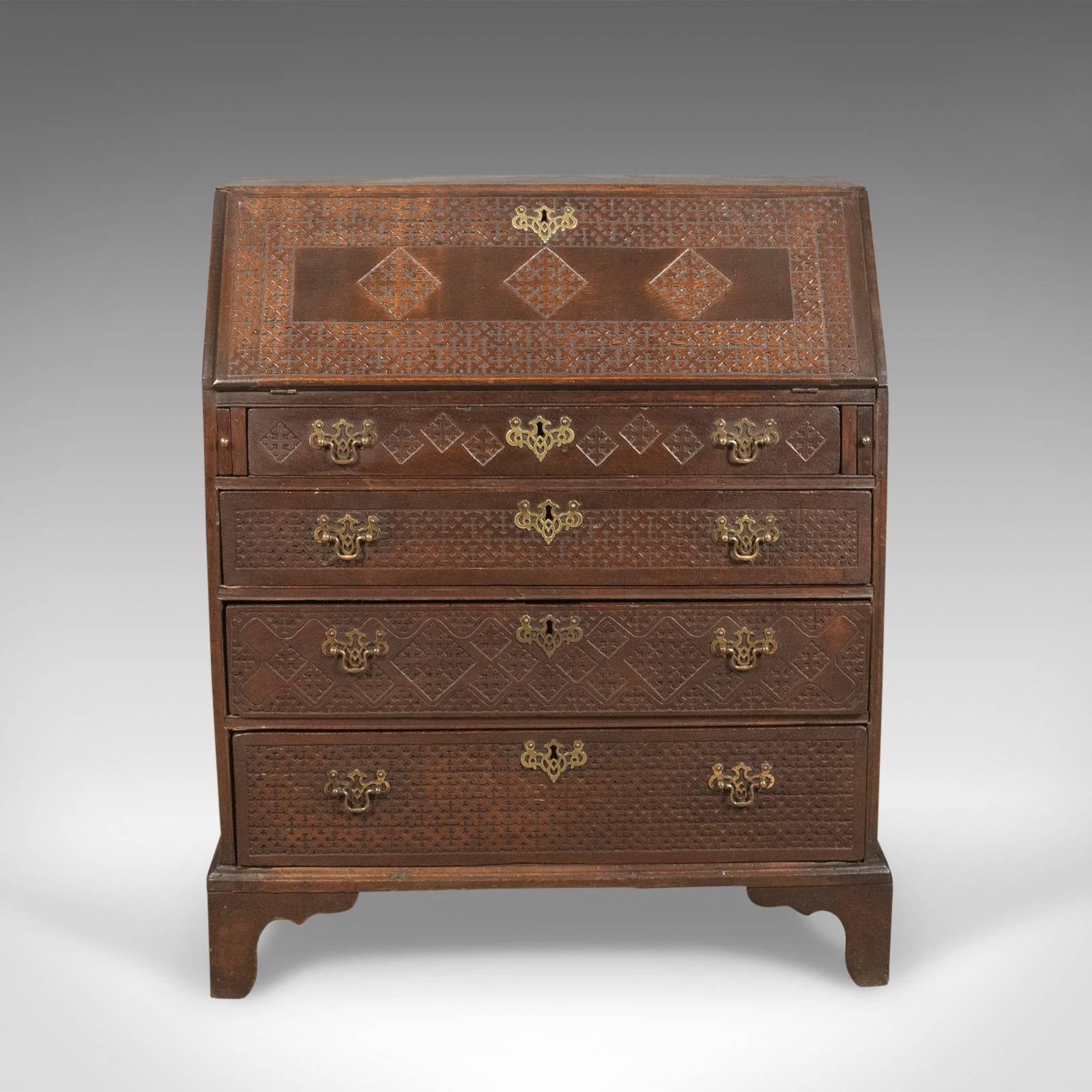 This is a late Georgian antique bureau in English oak. A writing desk dating to circa 1800.

Warm country feel and a desirable aged patina in the wax polished finish
Profusely decorated with blind fret geometric decoration
Standing upon Georgian