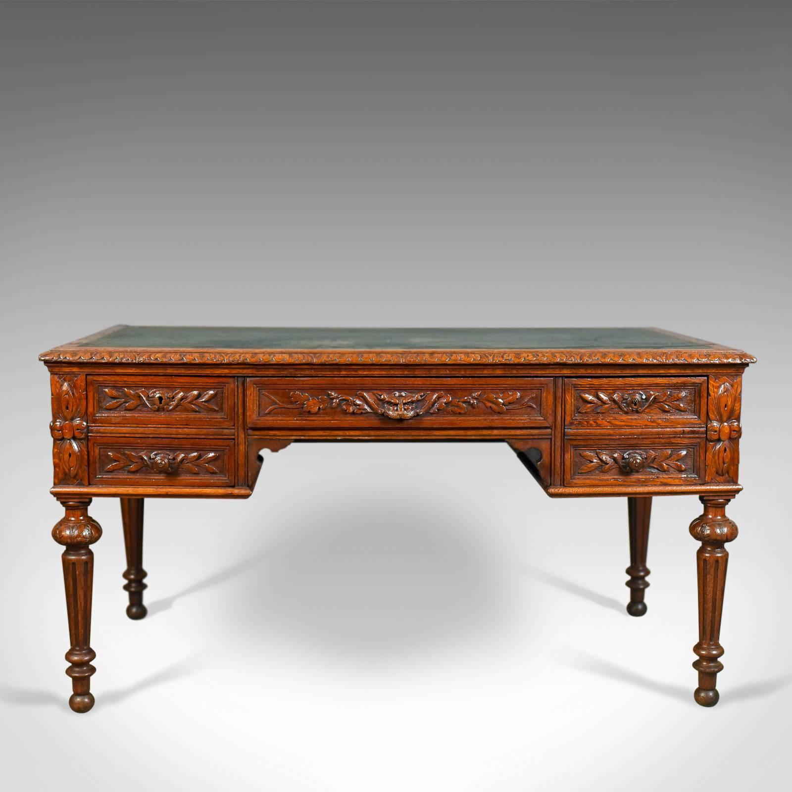 This is an antique writing desk, an oak, green man, Scottish table dating to circa 1890.

Delightfully carved all round, ideal for centre room placement
Appealing russet tones to the oak with a wax polished finish
Inset, Oxford green, tooled