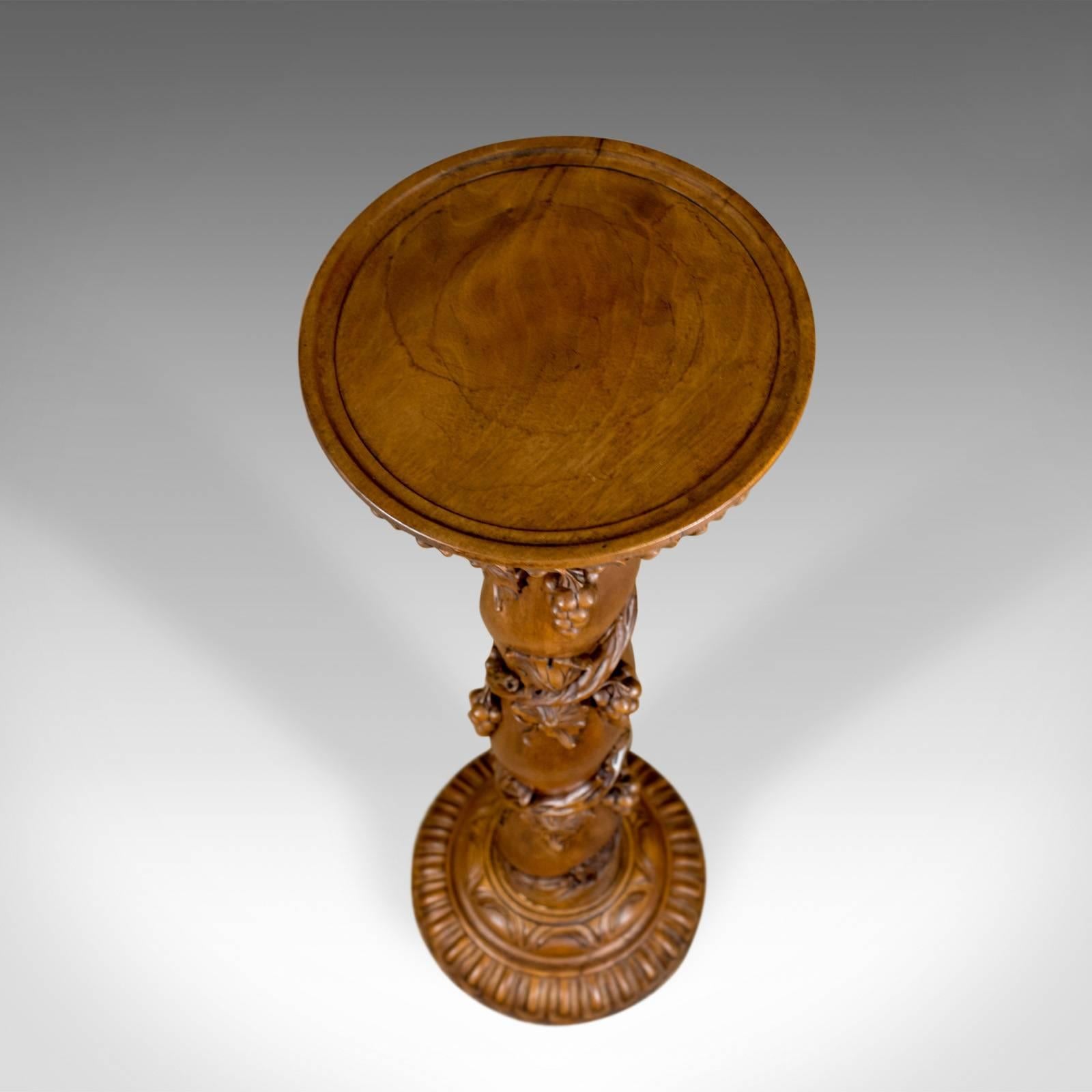 This is a midcentury plant stand, an English, mahogany torchère or pedestal decorated with carved grape vine.

Superb carved detail to this robust pedestal plant stand
Well executed, deep relief and pierced carved grape vine decoration
Winding