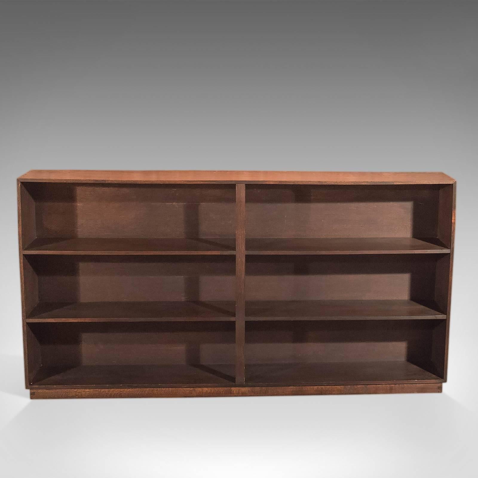 This is a Mid-Century open bookcase in English oak.

In classic six sectional form following early Georgian influence, this practical book shelf offers extensive storage with shelves eleven inches high and nine and a quarter deep.

Raised on a