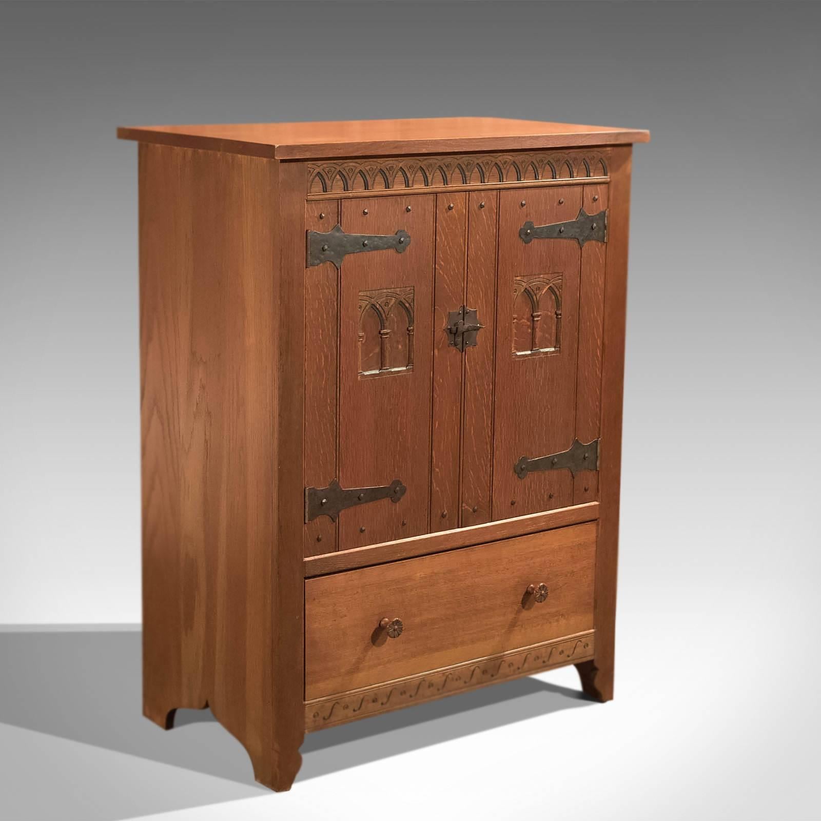 This is a vintage Mid-Century high quality oak cabinet in the tradition of the Arts & Crafts movement.

Raised on shaped feet and in good proportion, the two door cabinet sits above the single, deep drawer, unfussy and dressed with modest pulls