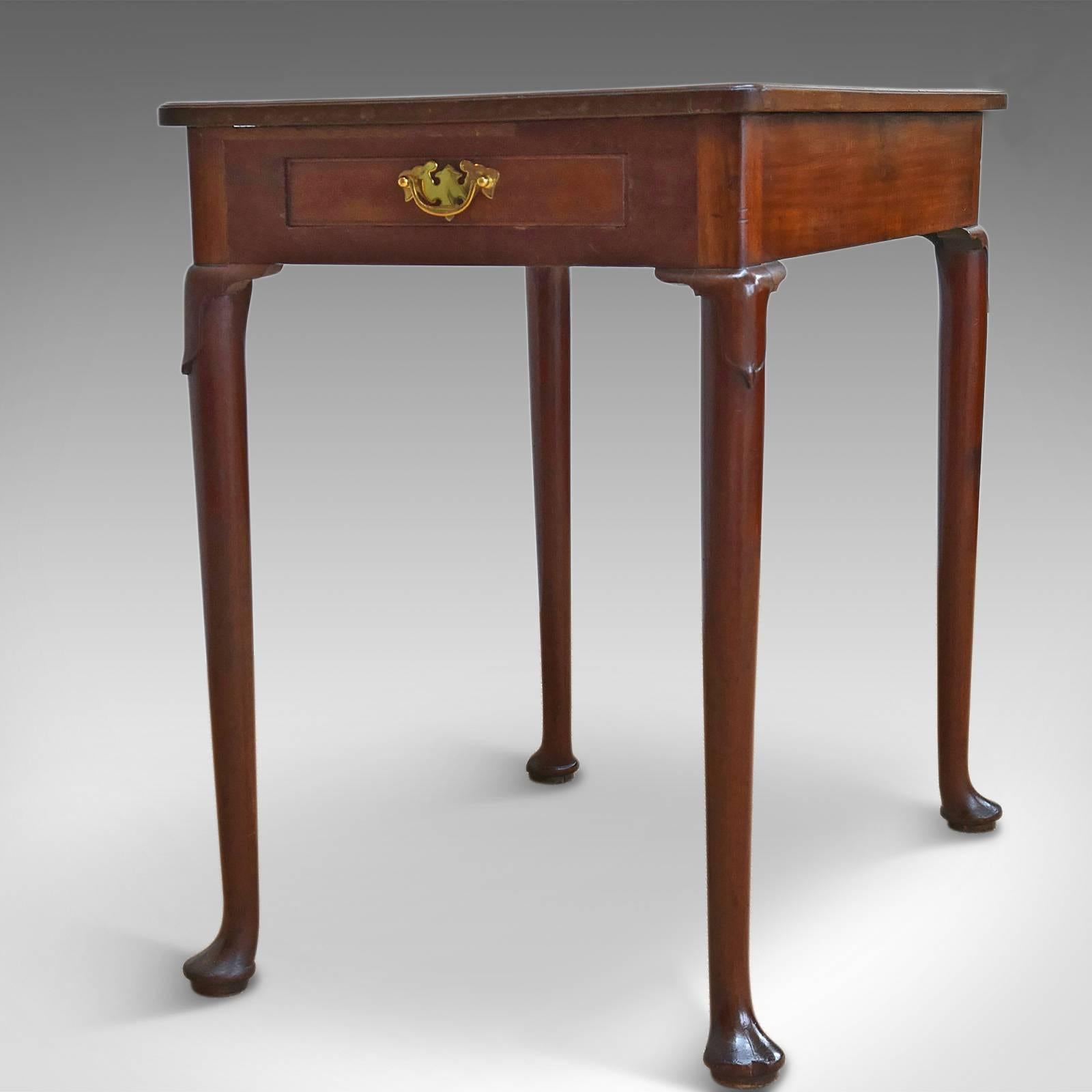 This is an antique side table dating to the early Georgian period, circa 1750.

English walnut with good color and grain interest
Simple moulded edge detail to the top and a desirable aged patina
Raised on slender, tapered legs
Drape carving to