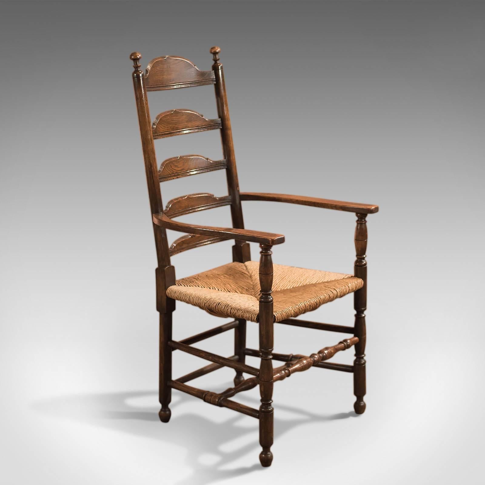 This is an antique Victorian ladder-back dining chair dating to circa 1900.

Raised on turned legs united by a box stretcher this carver is in fine order crafted in English oak with a rich warm patina and good colour.

The shaped armrests sit