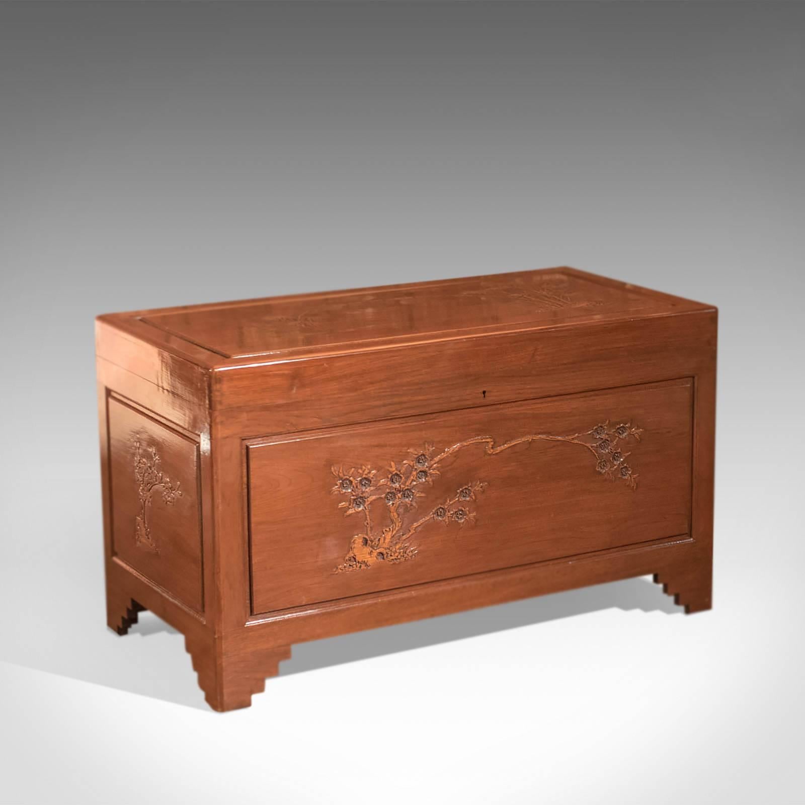 This is a Mid-Century camphor wood chest.

Highly polished, this chest is raised on stepped bracket feet, typically found on oriental storage furniture of this type.

Each face of the trunk features a field panel decorated with modest relief