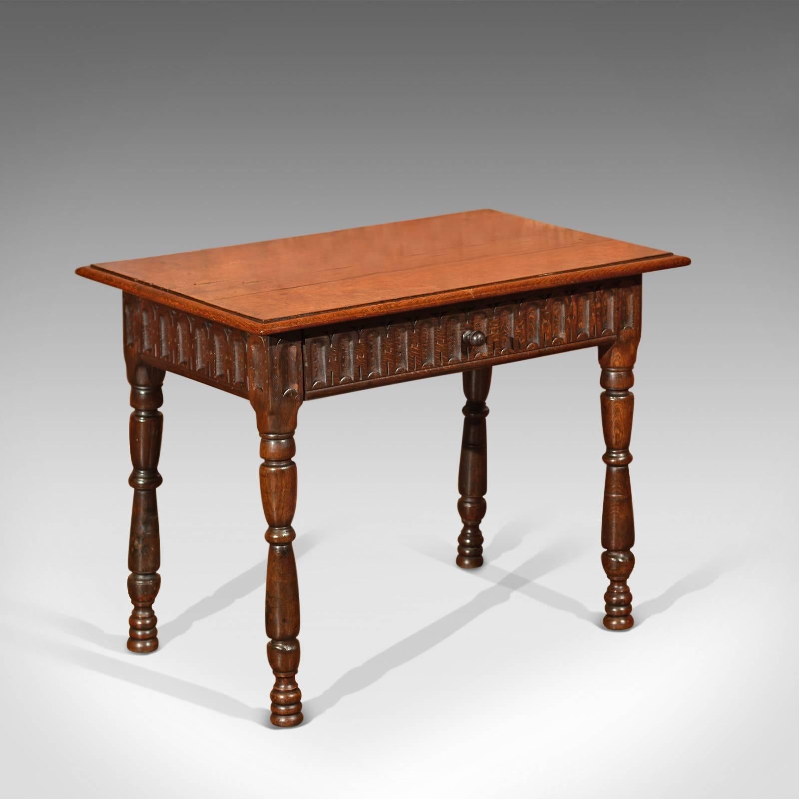 This is an antique side table dating to the mid-Victorian period, circa 1860.

Rising on unusual stout, flared and ring turned legs with triple turned 'hive' feet, this side table displays a carved frieze on all sides and a full width drawer with