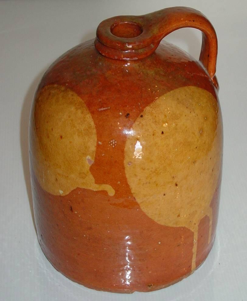 A one-gallon redware jug with bold yellow slip moon decoration. Manufactured in Galena, Illinois.