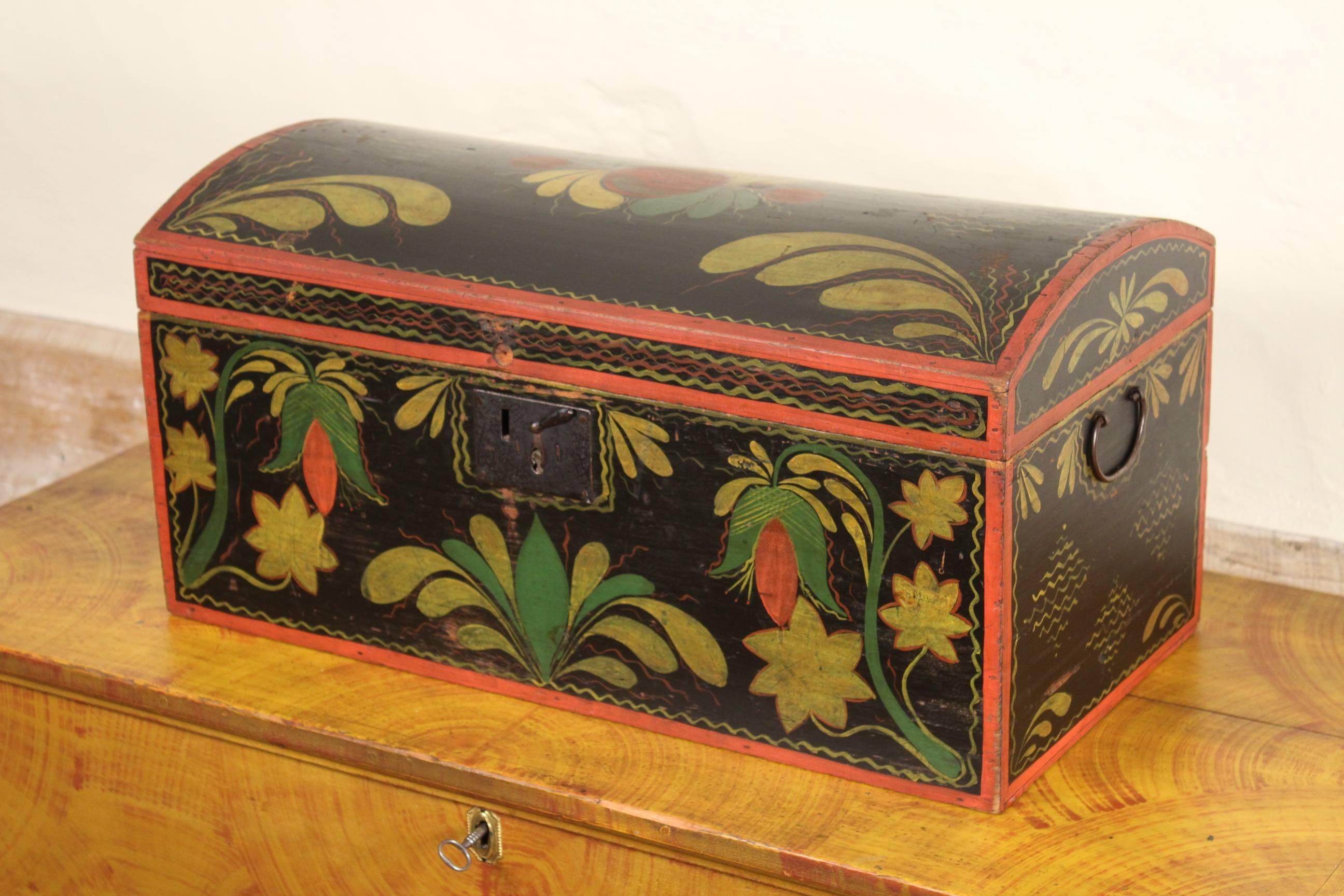 A dome-top trunk, probably from Rhode Island, featuring its original red, green and yellow floral and foliate decoration on a black ground. The interior retains its original lining composed of newspapers from Rhode Island dated "1827".