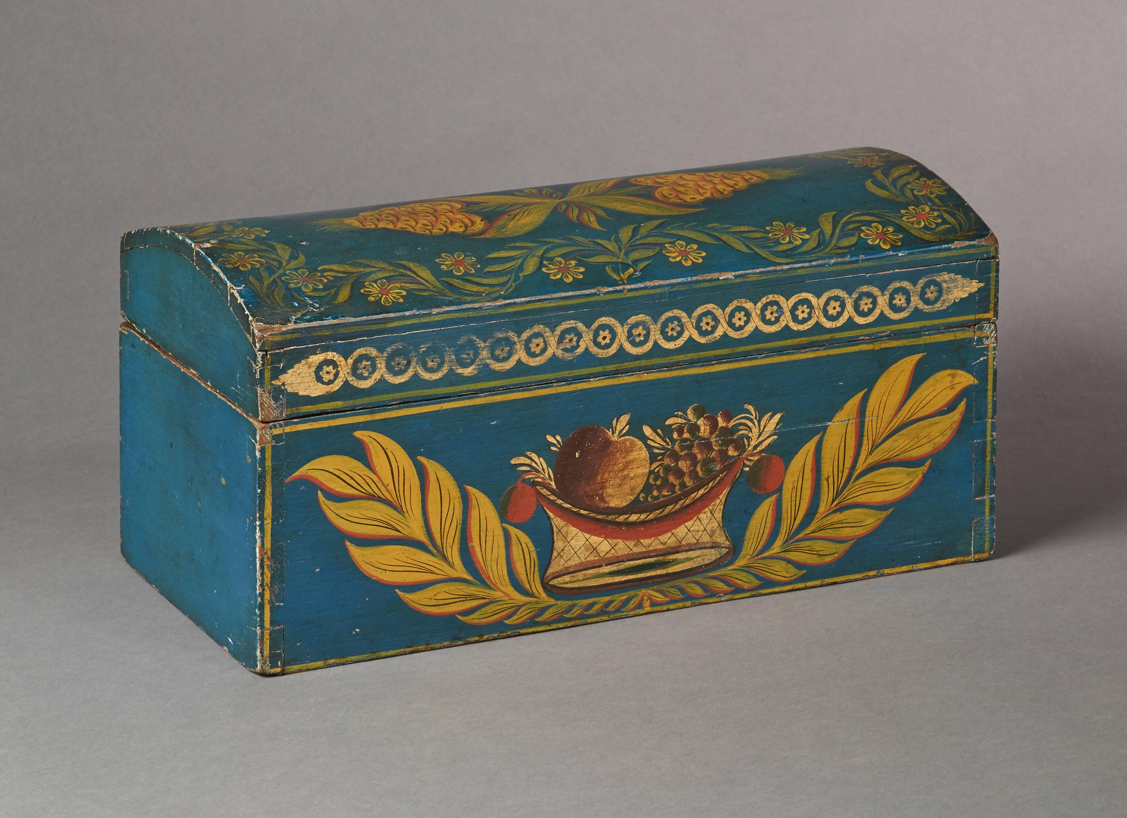 An exceptional New York state dome-top box featuring a polychrome and gilded basket of fruit and large leaves decoration over a brilliant blue ground. 

Provenance: Courcier & Wilkins; Private NY Collection.