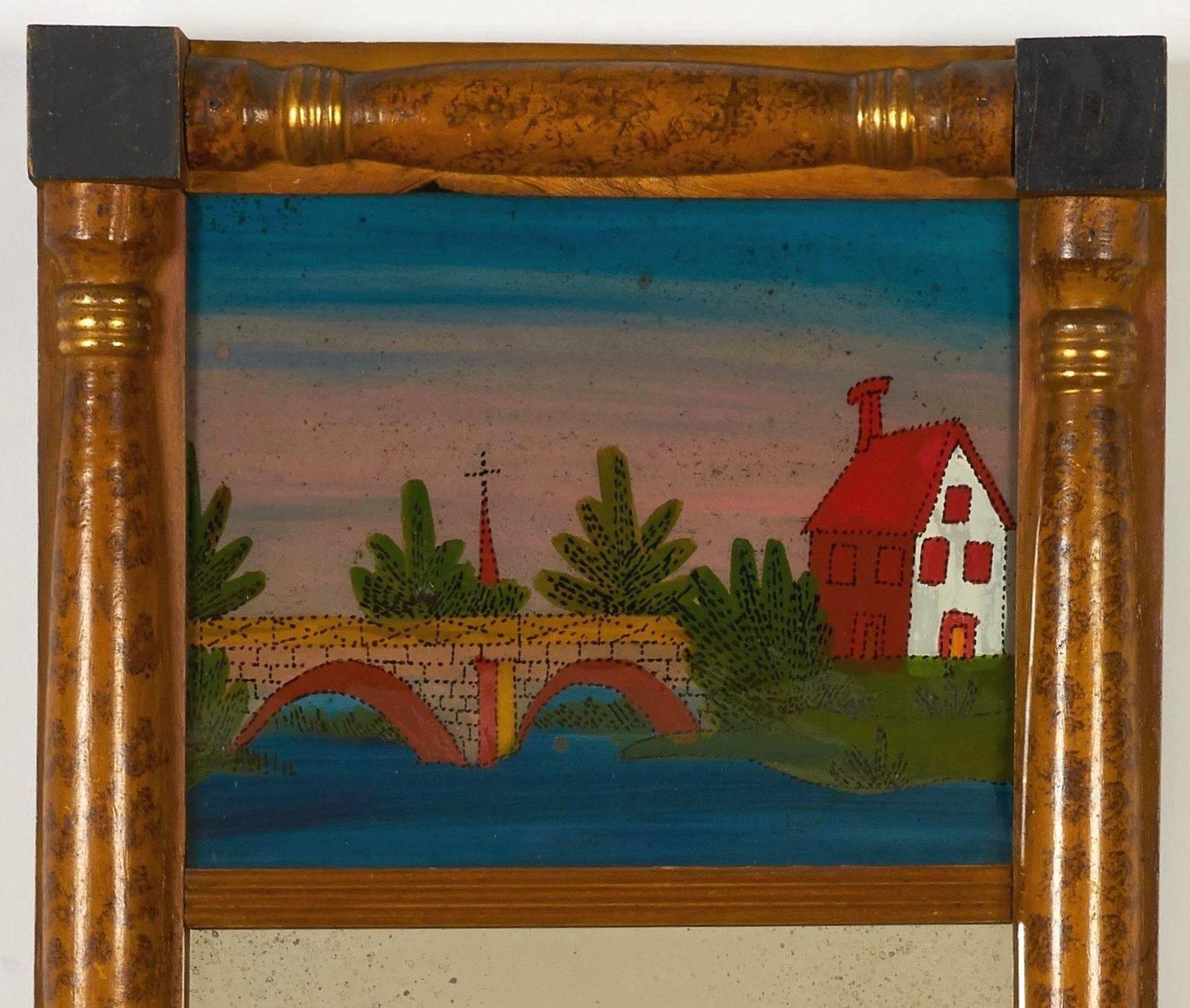 A classical painted and giltwood looking glass featuring a charming églomisé panel depicting a cottage by a bridge.