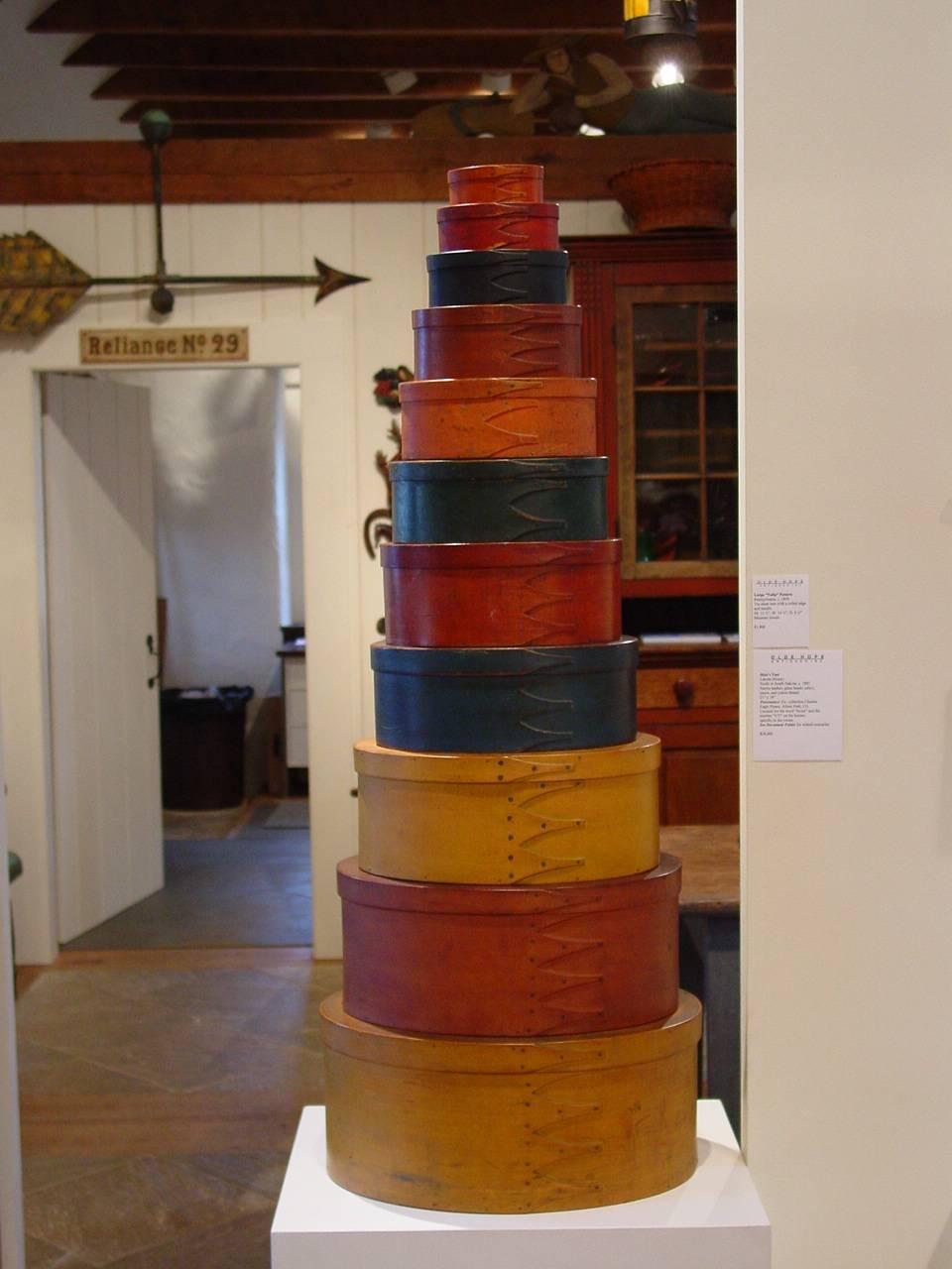 An exceptional stack of eleven Shaker finger-lapped oval boxes in a variety of original painted and stained finishes, including ochre, blue, green, salmon and red. From New England and New York communities. The 9 ¼” box from the Stokes Collection