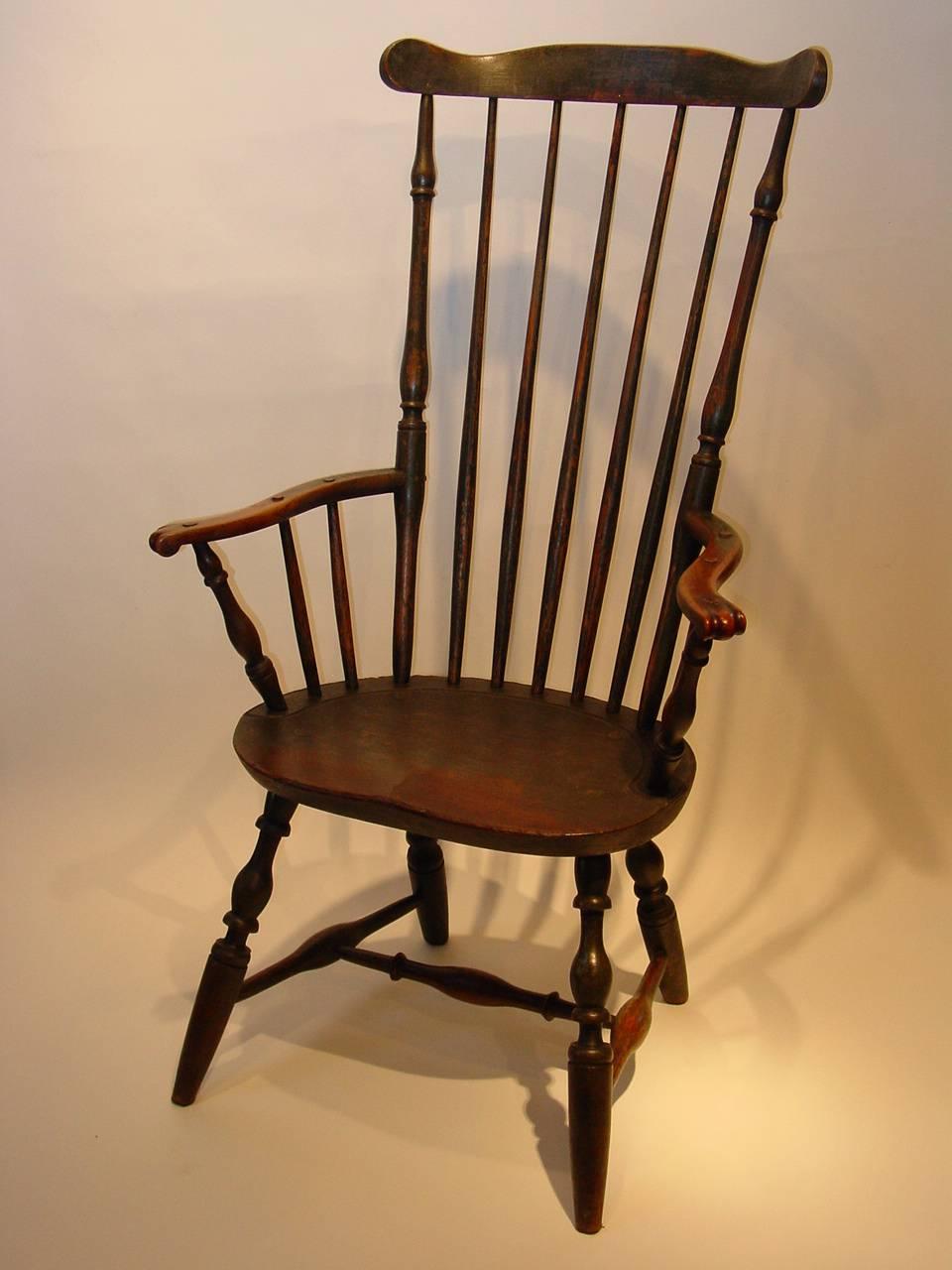 By an unknown maker, probably in Rhode Island, this fan-back windsor armchair is constructed using mixed woods and retains its original green-painted finish over a gray primer coat. The arms terminate in expertly carved knuckles well-worn with