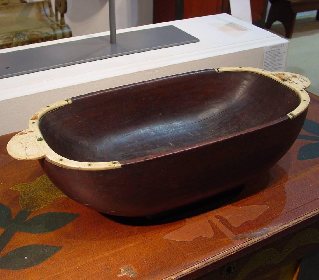 An exceptional carved hardwood bowl or trencher embellished with carved bone handles. Retaining a wonderful rich, warm patina, this bowl was likely made by an American sailor while at sea using materials acquired at ports of call. 

Provenance: