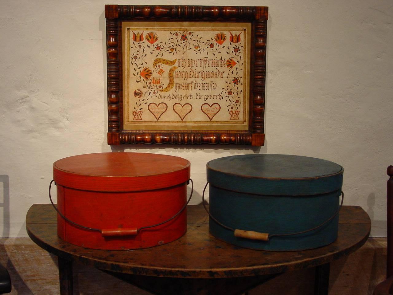 An assembled pair of large painted pine and hickory pantry boxes in beautifully complementing blue and bittersweet red. These country pantry boxes were made in New England and feature iron bail handles. Both pantry boxes are in exceptional condition