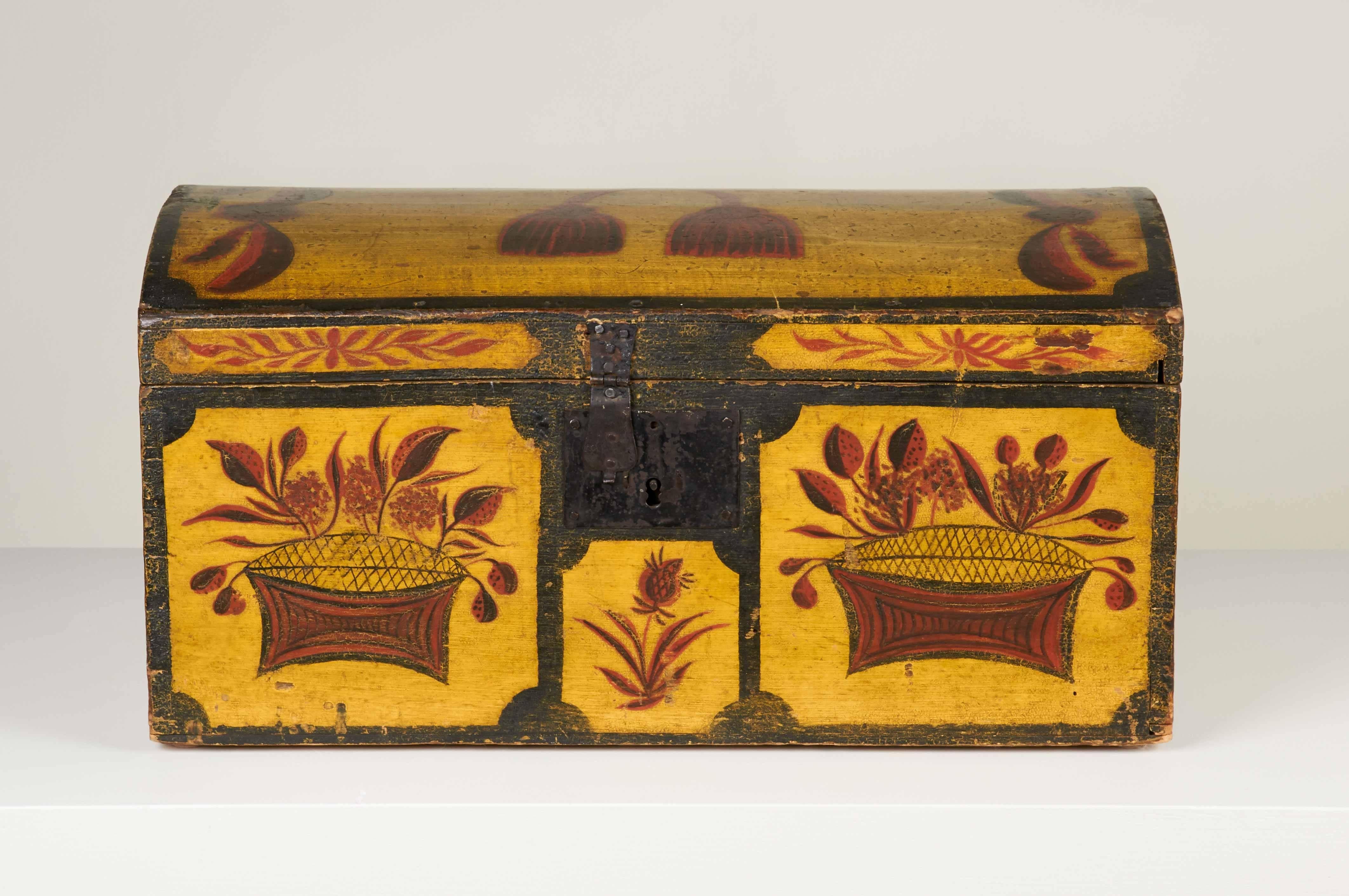 A superb Folk Art dome top box from New York State featuring a vibrant yellow ground, outlined in black, on which are painted red and black floral and foliate motifs as well as a tasseled swag which adorns the top. The box is constructed of pine and