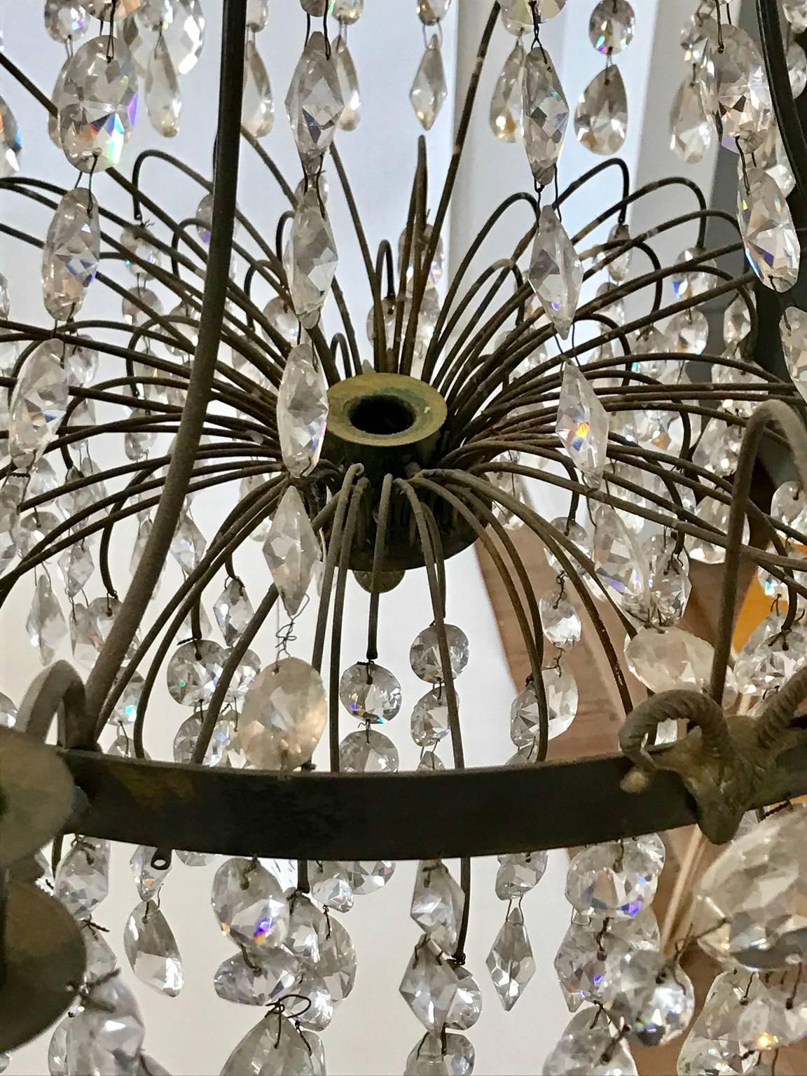 Delicate early 19th century crystal chandelier of basket-form; eight scrolling arms to support candles, with another candle holder at the center bottom of the basket; gilt bronze armature; two later small electric light fittings at the top ring of