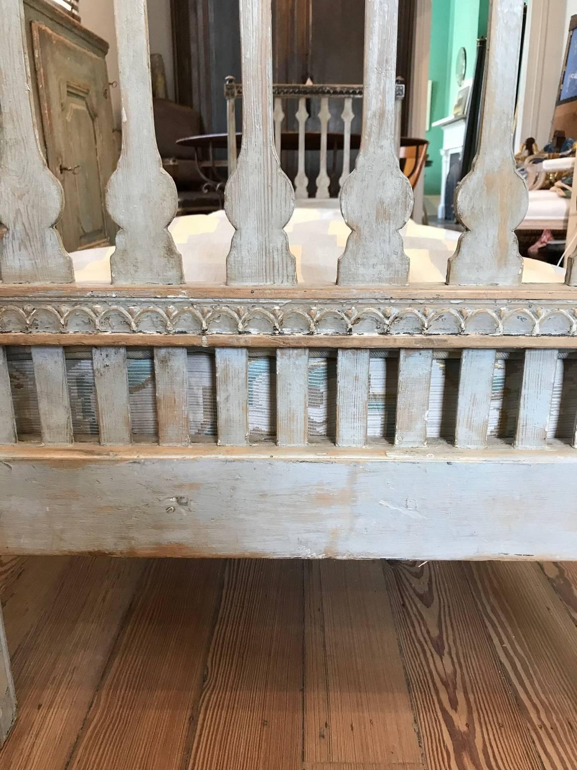 Long Gustavian daybed or bench; the ends with baluster-form splats and attractive carvings at the top and bottom rails and rosettes at the corner blocks; square legs with channel detail; later paint removed to show original gray color; the top rails