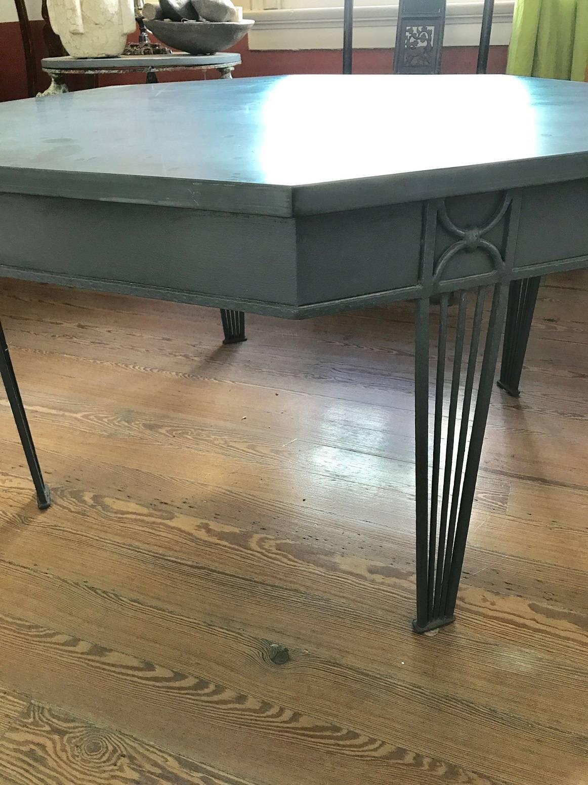 Impressive octagonal table of generous scale with painted iron base and thick slate top; can be used as a dining table, center table, or garden table; the iron painted slate blue to match the top; width measurement below is for flat side to flat