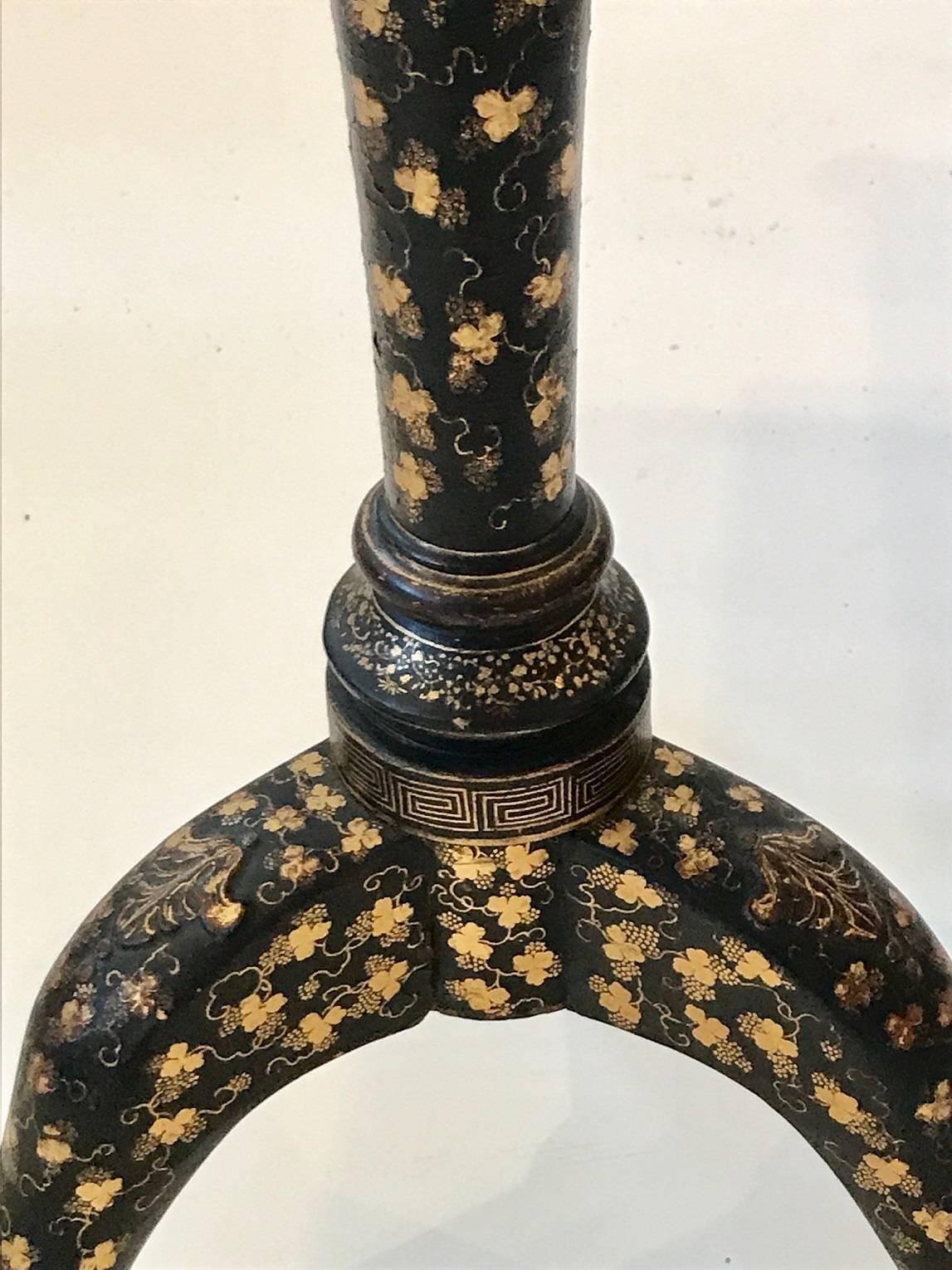 Charming export tilt top table in black lacquer with gilt and foliate stencil decoration tripod base with modified ball and claw feet; nicely detail bird cage support on turned baluster-form pedestal.