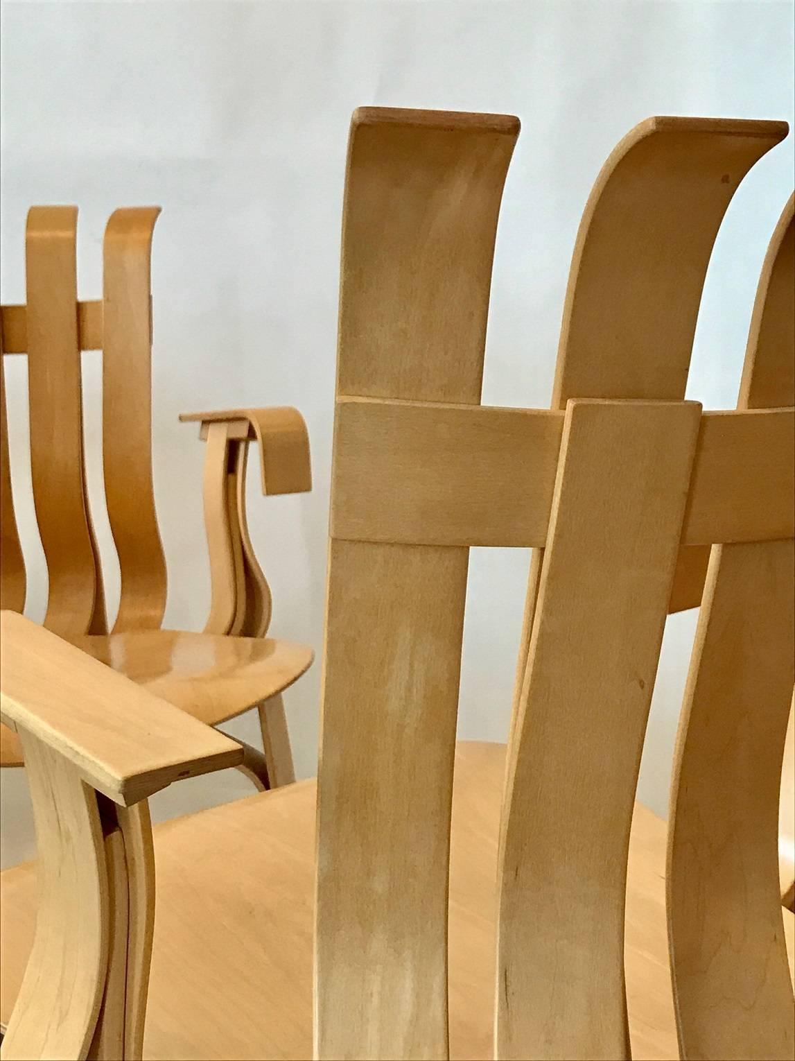Two iconic "hat trick" armchairs designed by Frank Gehry in 1992 for Knoll; the back and legs in bent laminated maple veneer strips; the seat in maple cross-ply veneers; plastic glides; each marked with the Knoll logo and date of