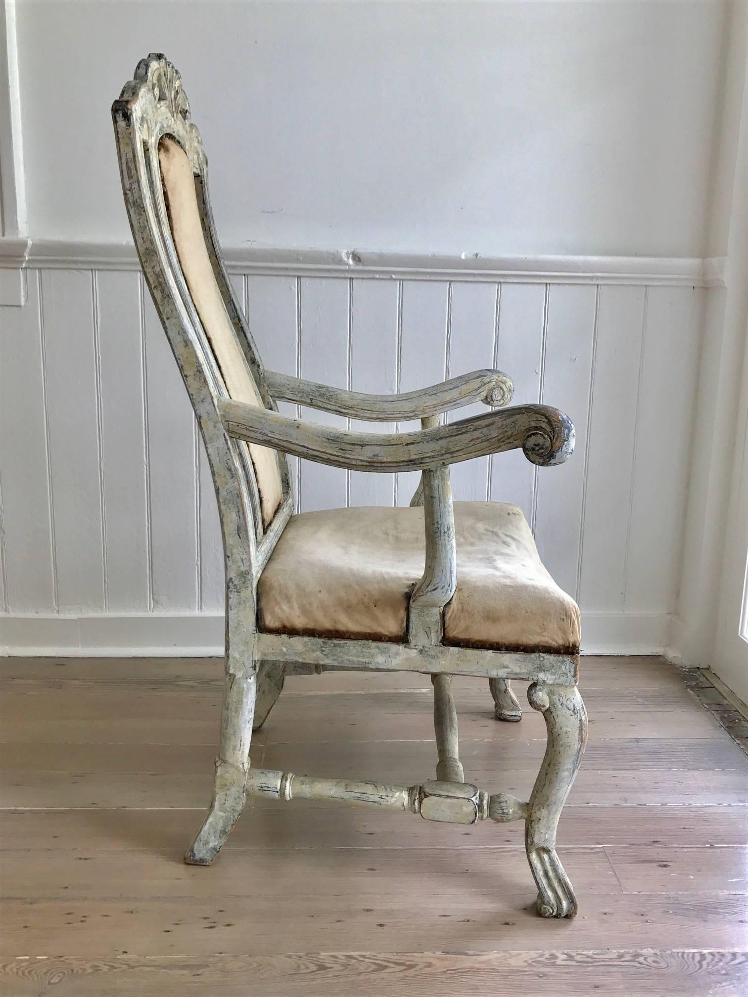Robustly styled and carved Swedish Baroque armchair with original cream colored paint, now worn to a very attractive patina; the crest rail and seat skirt expressively detailed; turned h-shaped stretchers; upholstered back splat and seat.