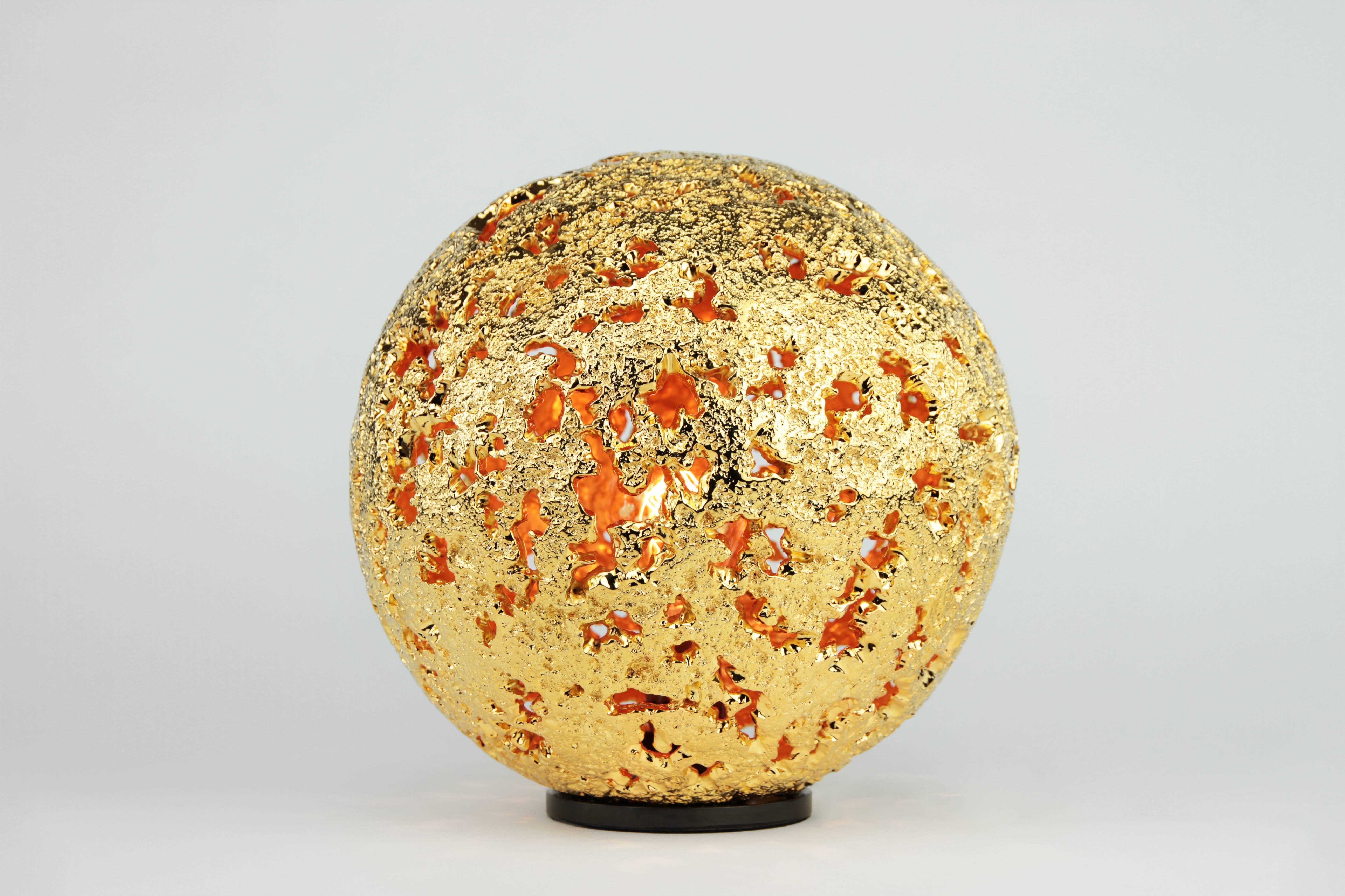 The one-of-a-kind Hot Planet Table Lamp is a 22K gold plated bronze sphere of hand sculpted craters.  The central light source is symbolic of our planet's core. The body is cast in bronze then plated in 22 Karat gold, then high polished. The high