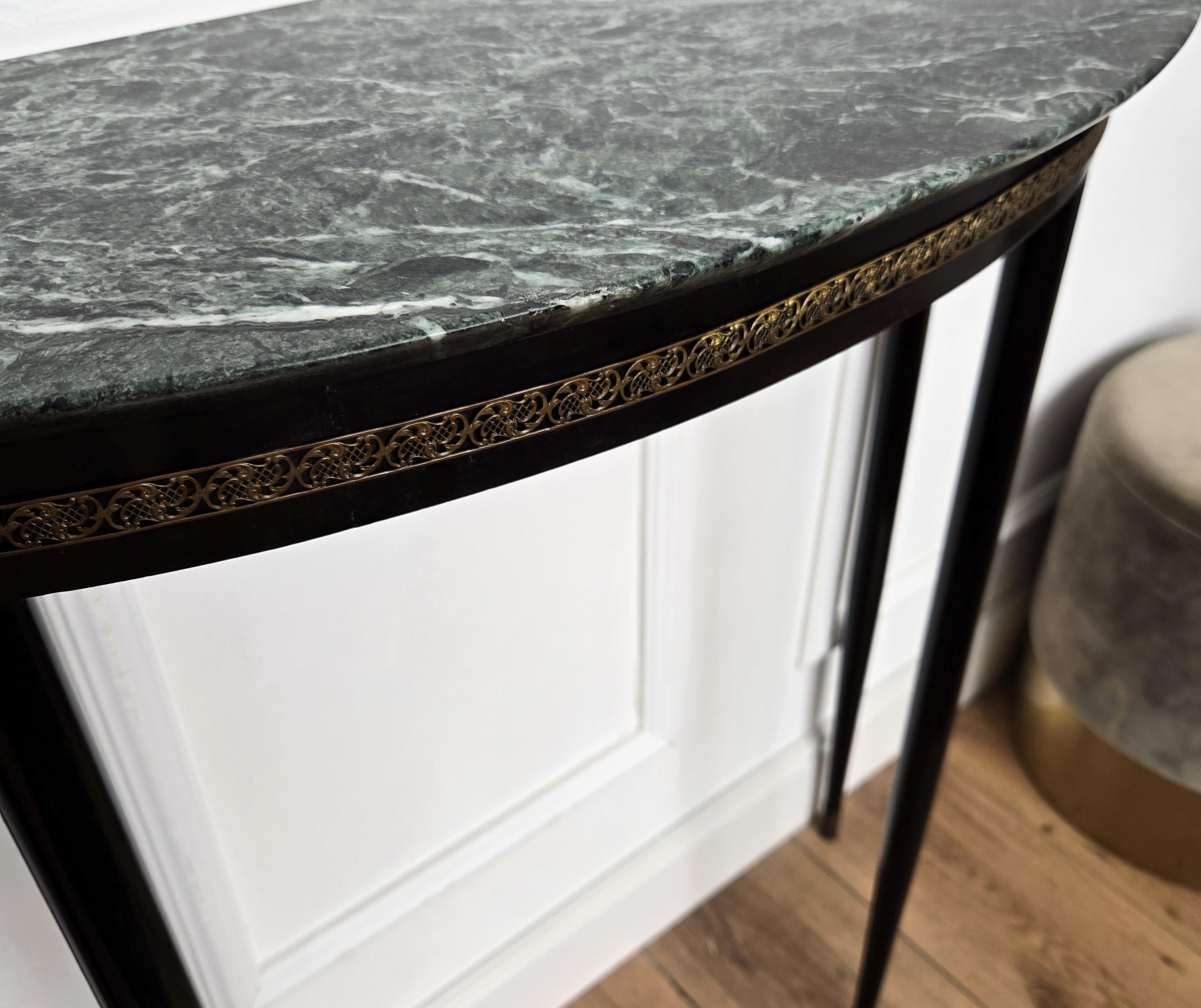 Very elegant and refined Italian 1950s Mid-Century Modern Neoclassical design console table. The brass decorated structure and cone shaped legs with its typical green marble beveled top give this console an extremely light and open aesthetics. This