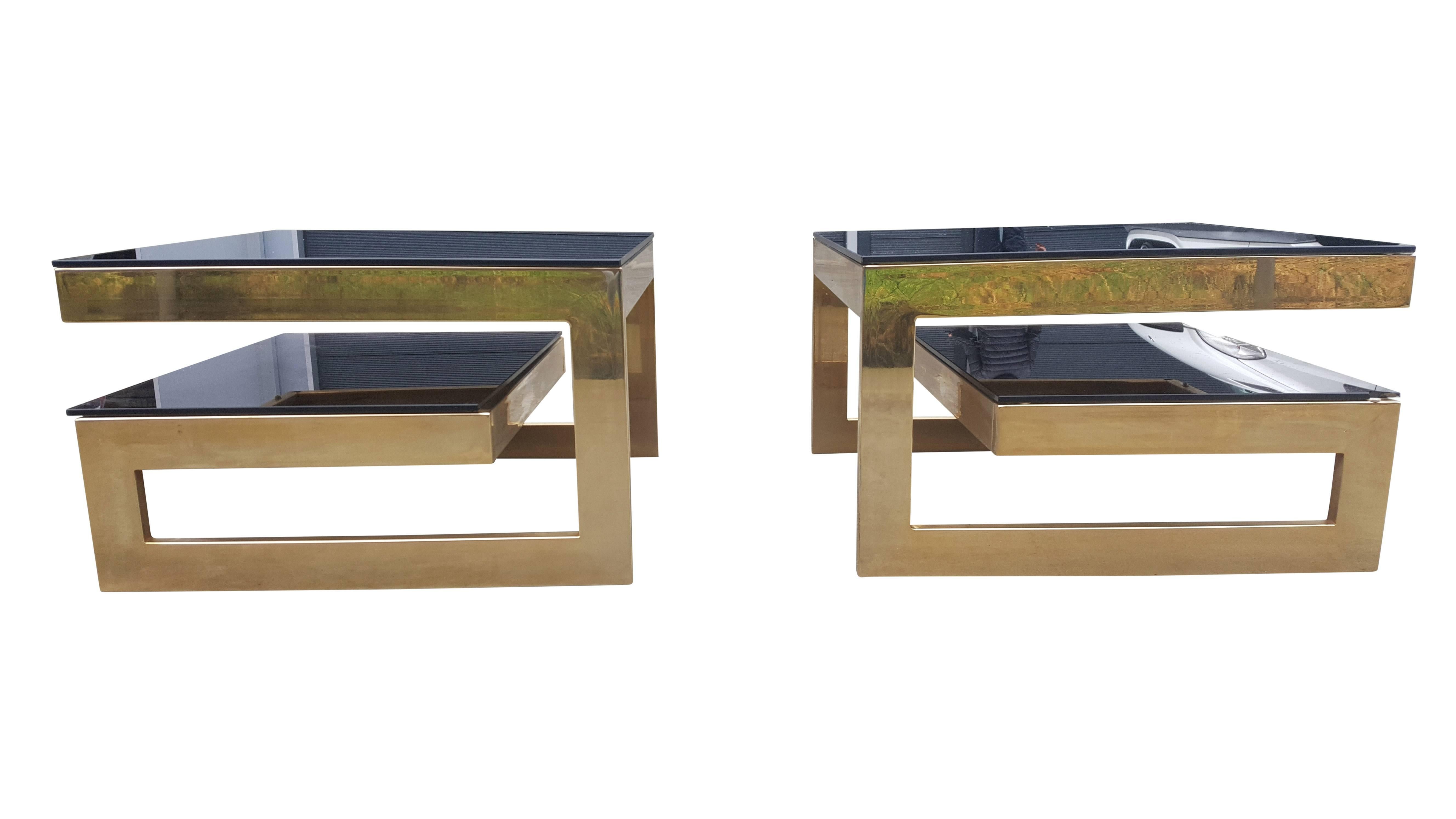 Iconic G-shaped pair of coffee tables from Belgo Chrome.
In the style of Maison Jansen. 
The upper and bottom level has dark glass.
The gold on the frame is in a very good condition! 
The table is made in Belgium in the 1980s.
 
