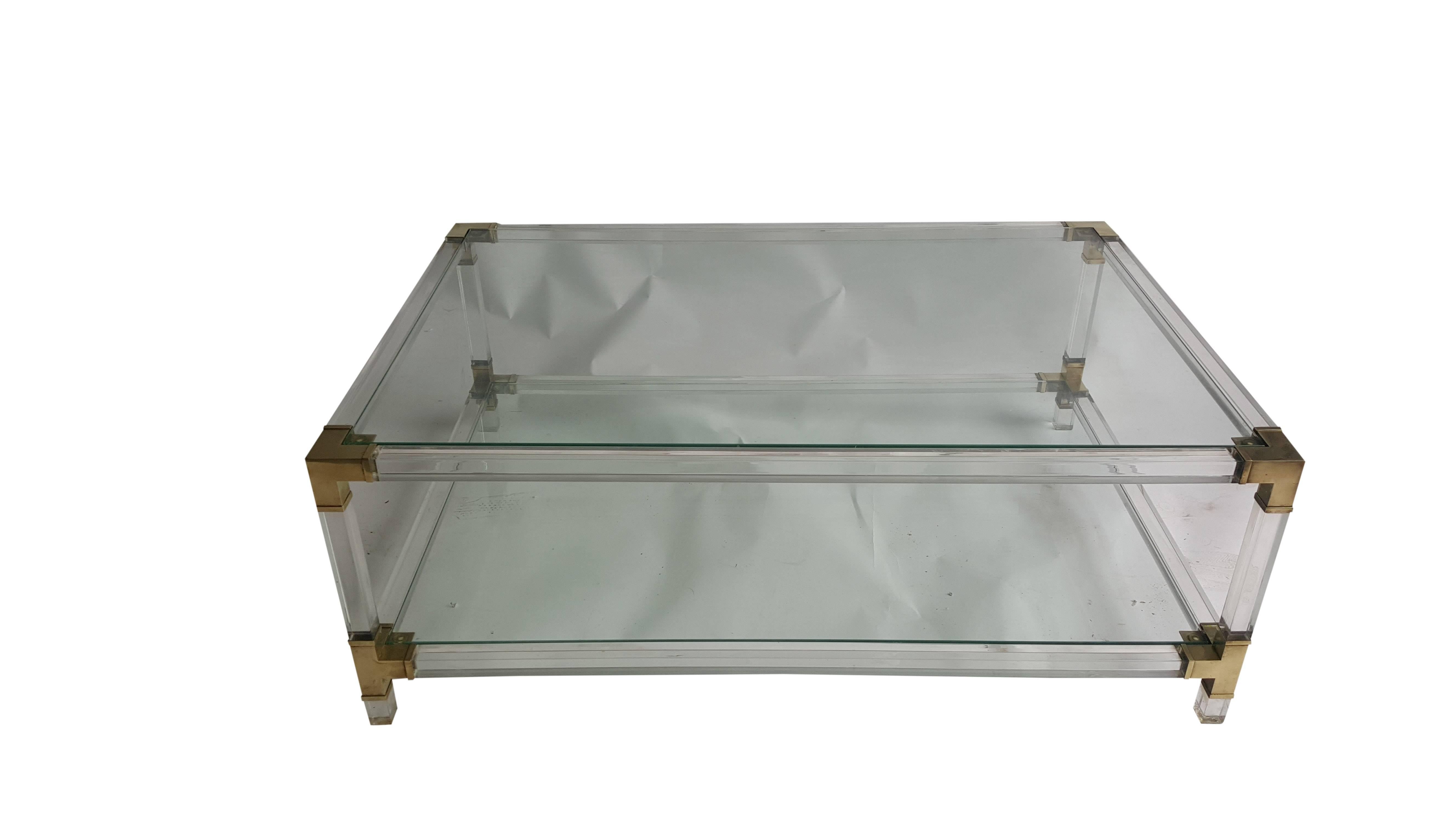 An amazing coffee table!
This table has four poles that are supporting tabletop and shelf on the bottom.
Each pole has decorative brass element on top and bottom.
Coffee table is made out of thick plexiglass.

Condition is excellent!

Stylish