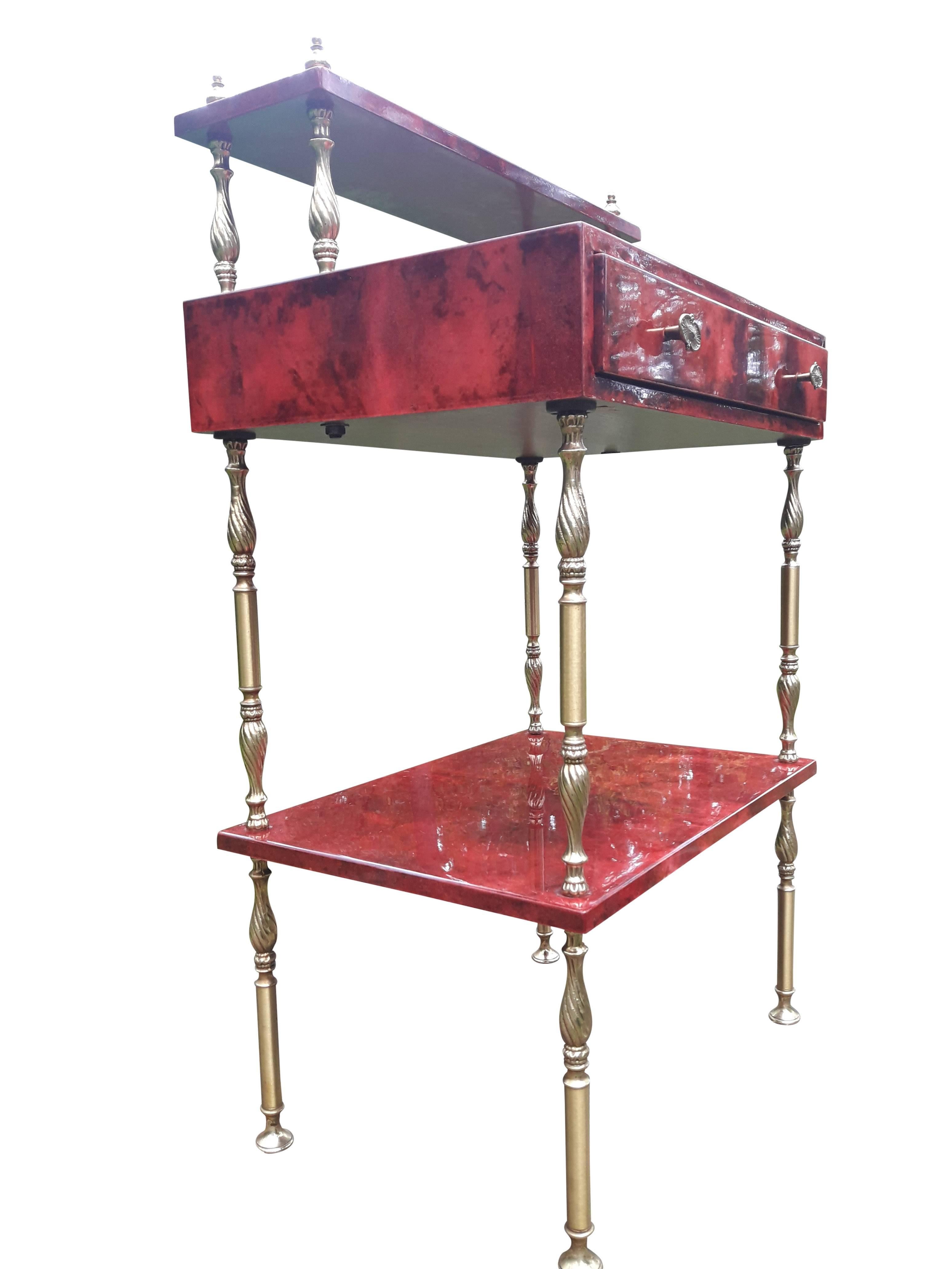 Aldo Tura red goatskin parchment side table with one drawer(scratch, see pict).
The table consisting to three levels and a drawer. 
Nice brass details. 
Aldo Tura started in the 1930s and fully developed in the 1950s a successful business
