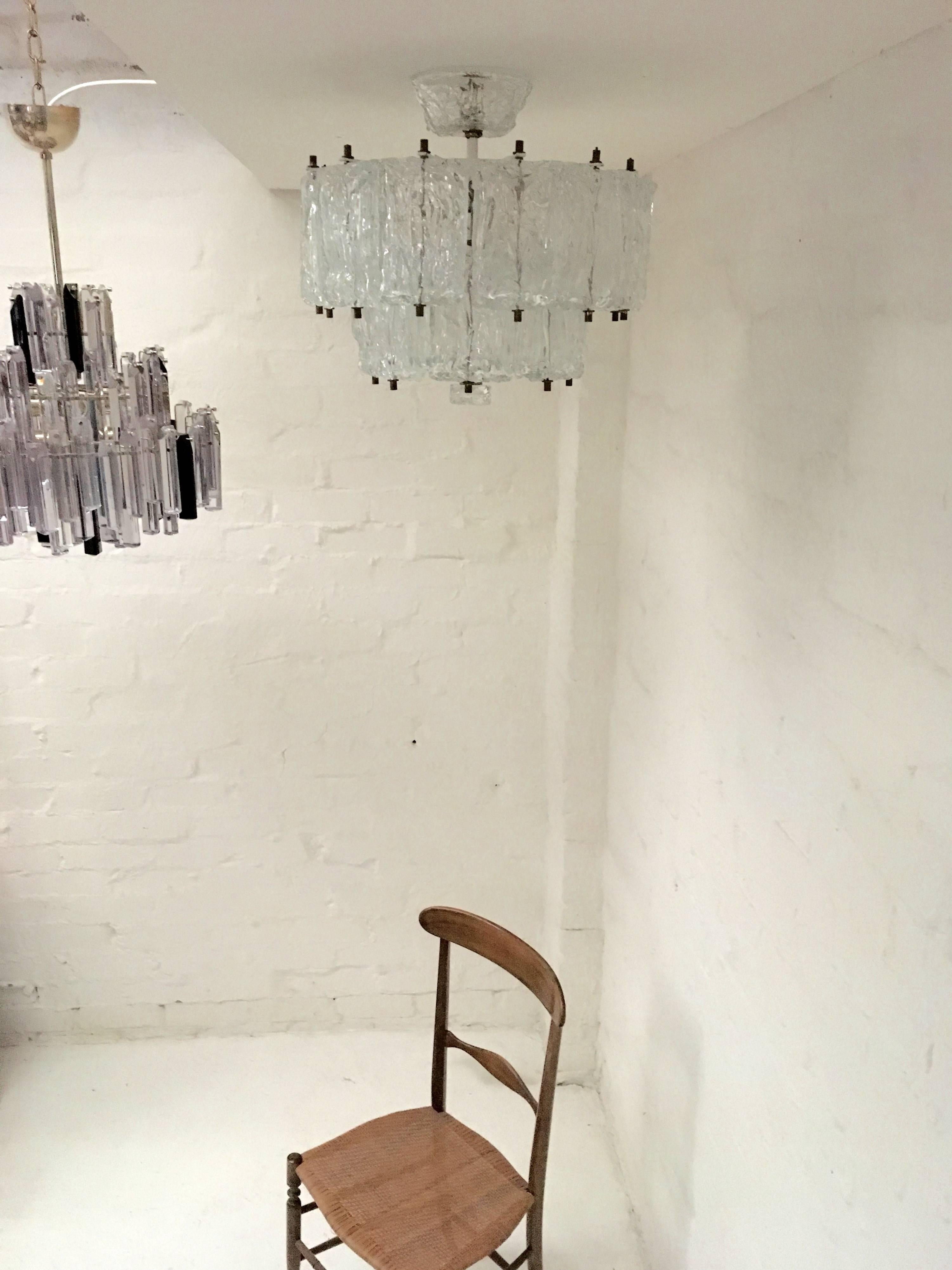 Perfect for smaller apartments and lower ceilings, this chandelier is designed to completely hide the light bulbs and to cling quite closely to the ceiling, with a relatively short drop of 40 cm.

The bricks or tiles that form this lovely