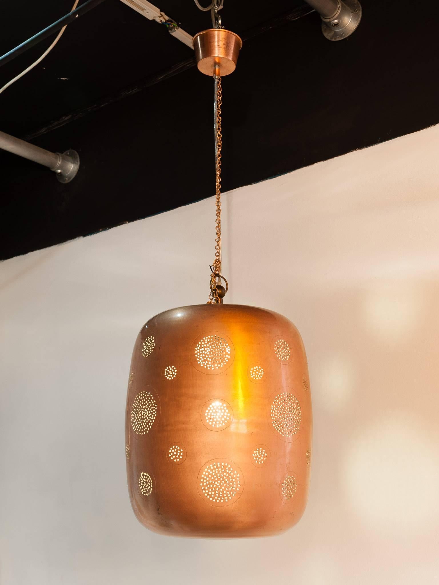 An unusual and striking punched hole pendant light which is handmade from solid copper. The light shines through the holes giving off a warm glow and creating patterns on the walls which produce a beautiful atmosphere throughout the room. A very