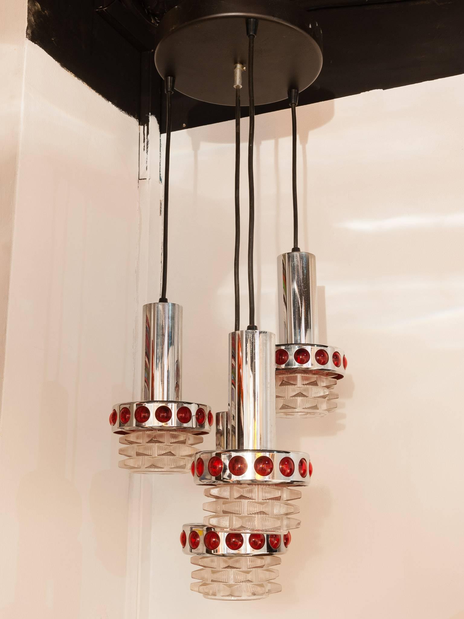 1970s Midcentury RAAK chrome hanging light with ruby red circular spotted decoration. The lamp has four shades which hang from a circular black metal disc ceiling plate which fixes to the ceiling. The shades are formed from glass, chrome and red