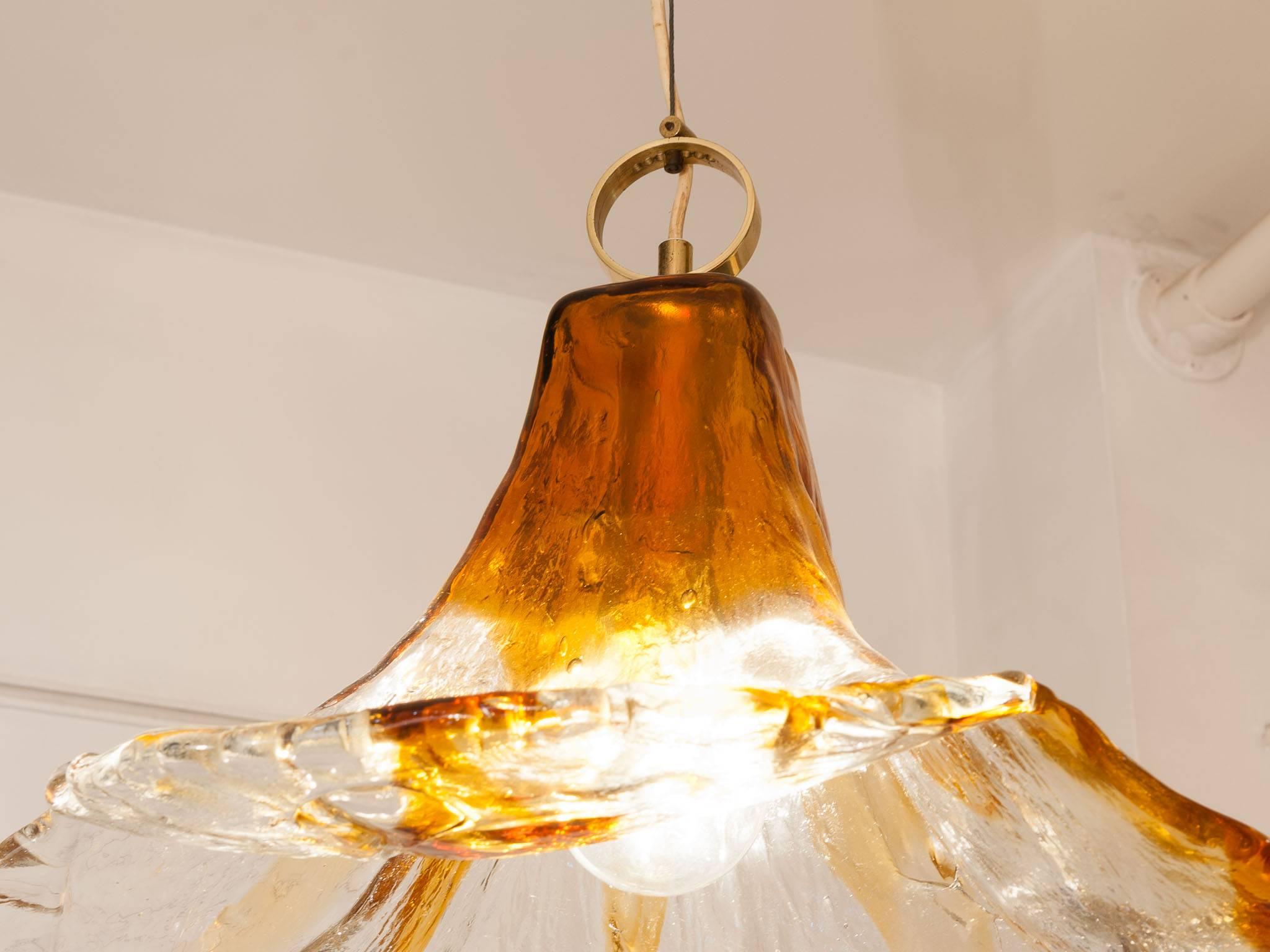 1970s Murano glass pendant hanging light by Mazzega in the shape of a flower with four petals. Handblown from one piece of glass with an orange and clear glass ripple design with a feature brass hooped fitting and ceiling cup. The light is quite