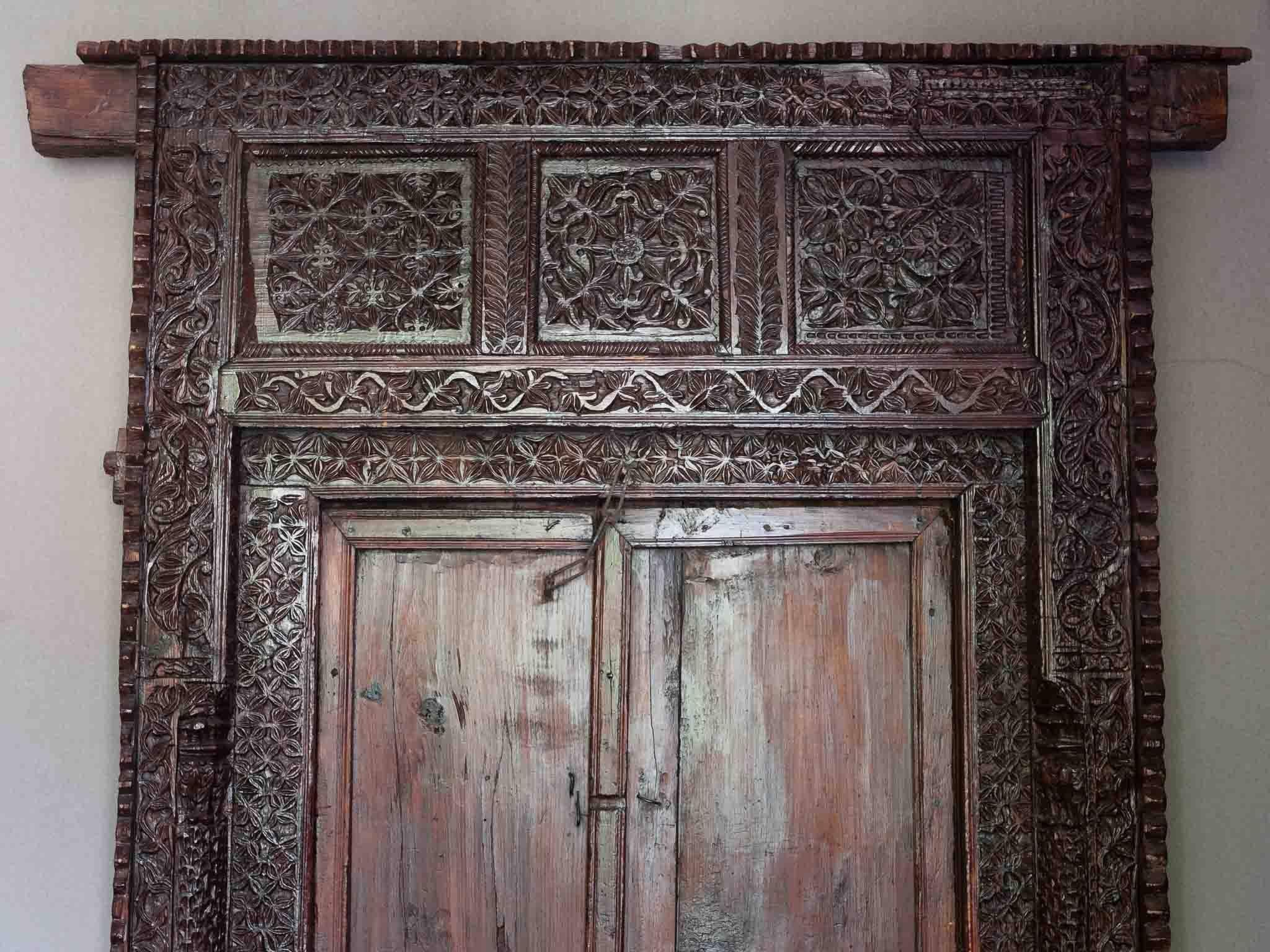 A stunning, ornately and intricately hand carved Indian door frame and doors dating back to the 19th century. The plain doors are easily removed from the back of the frame in order to move or transport the piece. The frame is wonderful as a