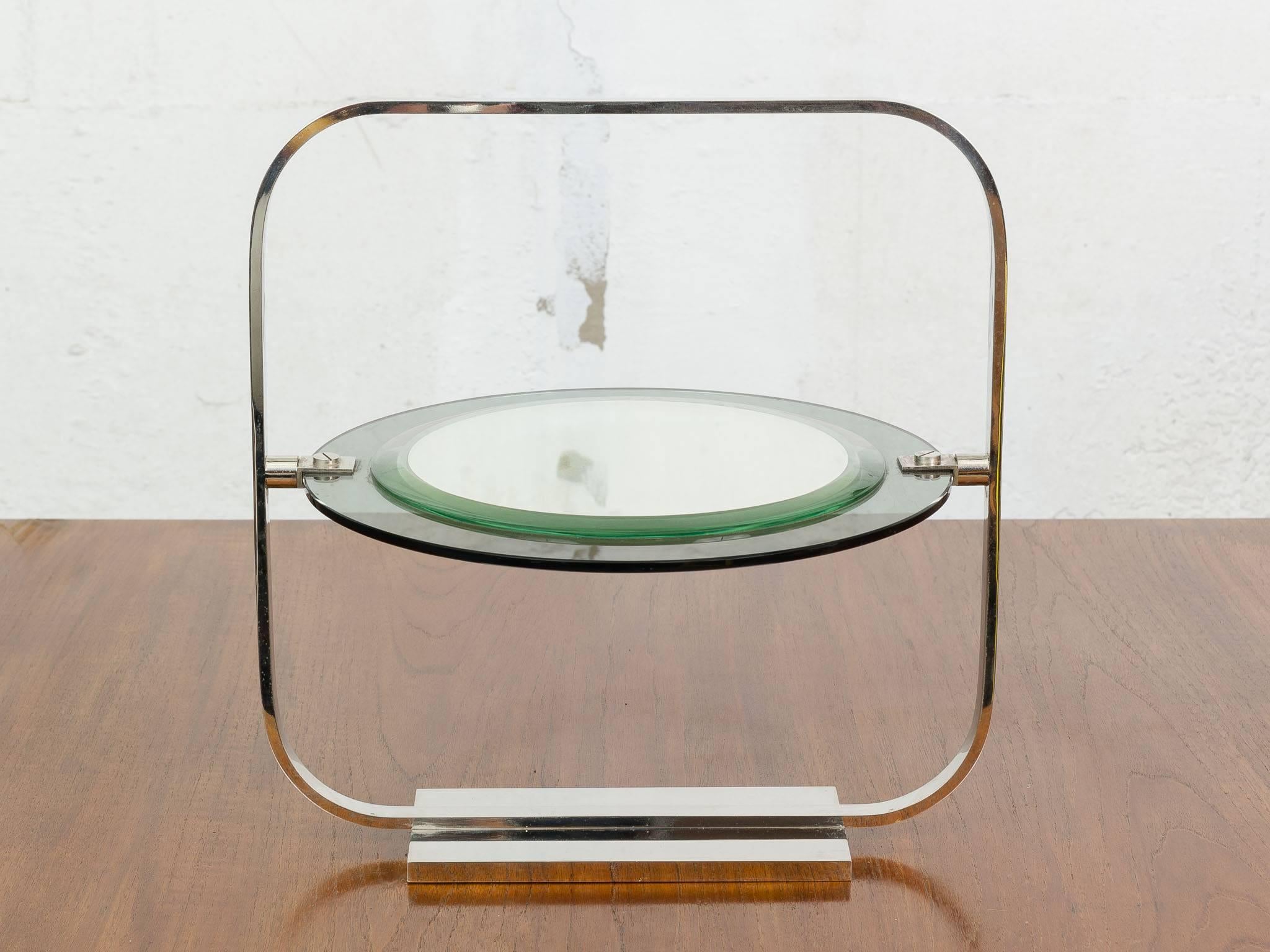 Vintage vanity table mirror by Christian Dior. The round swivel mirror sits within a solid chrome outer square frame with round edges. The mirror sits on two green tinted bevelled glass plates. One smaller than the other with two claps on either