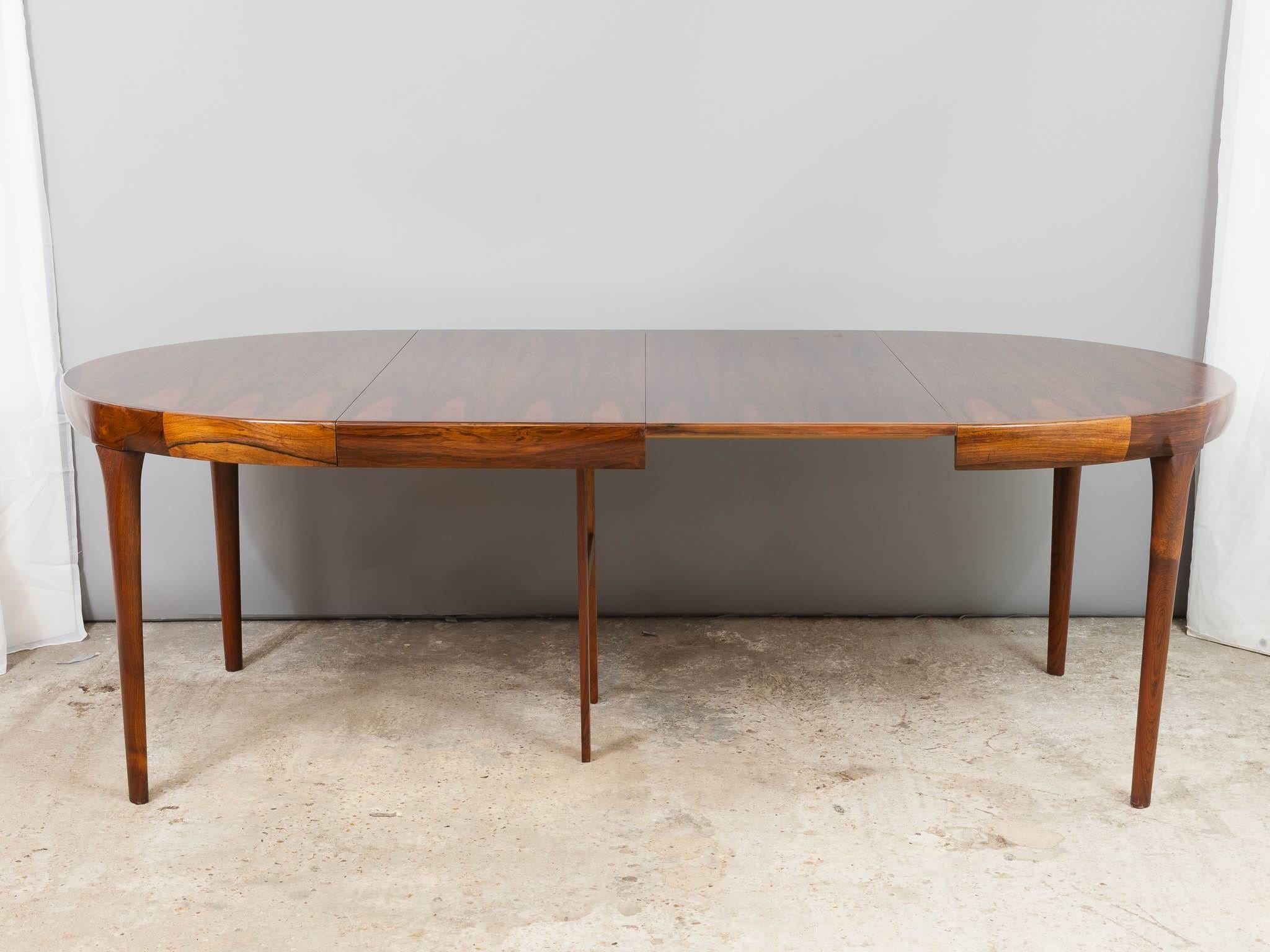 Mid-century Danish Rosewood extending dining table designed by Ib Kofod Larsen for Faarup Møbelfabrik. The table has been beautifully and painstakingly restored highlighting the wonderful deep grain, sleek sculptured lines, and tapered solid
