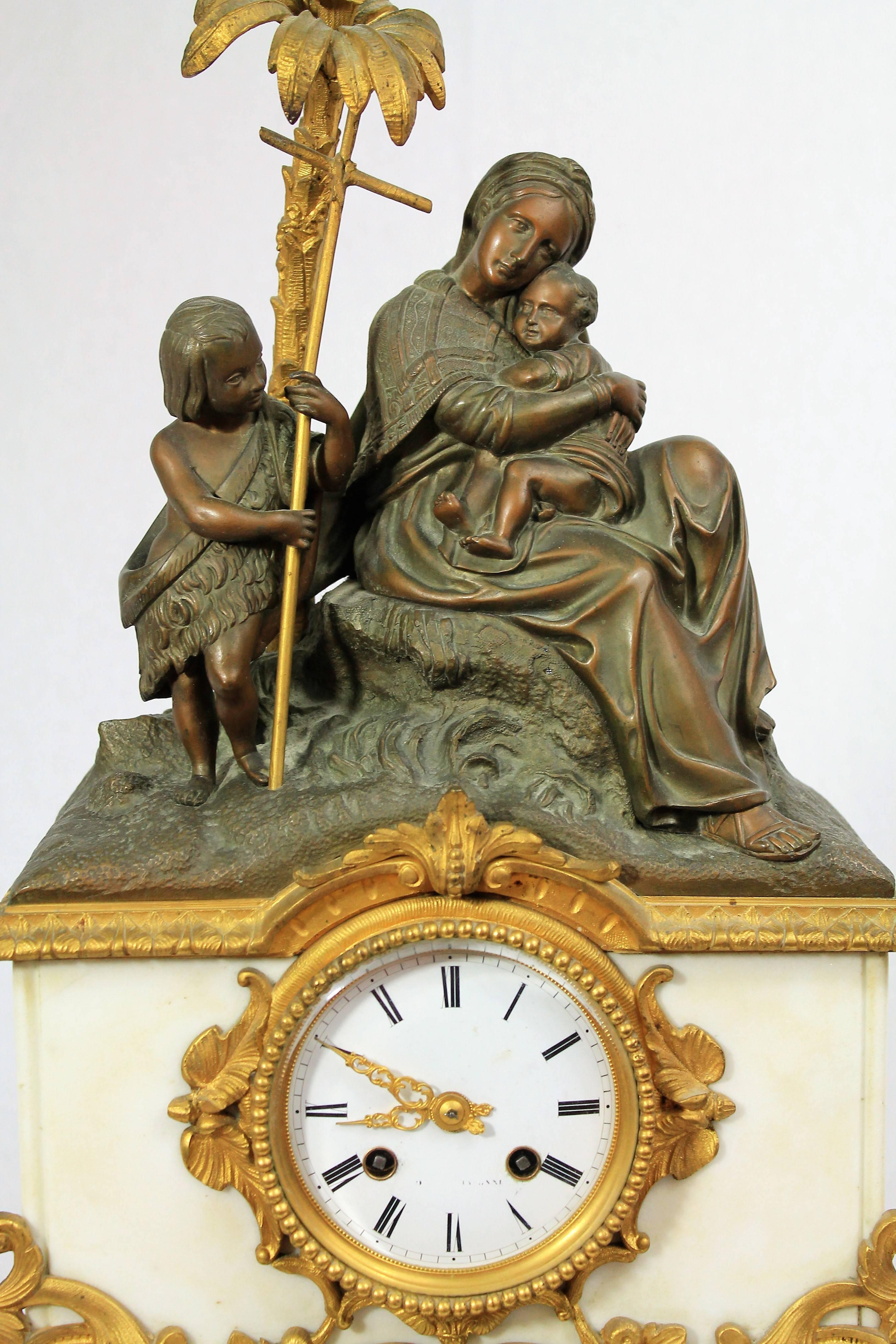 Very beautiful fireplace clock in marble, patinated and gilded bronze representing the Virgin Mary sitting on a rock holding the infant Jesus in her arms, with at their side st John the Baptist child holding his crosier.

Beautiful bronze patina,