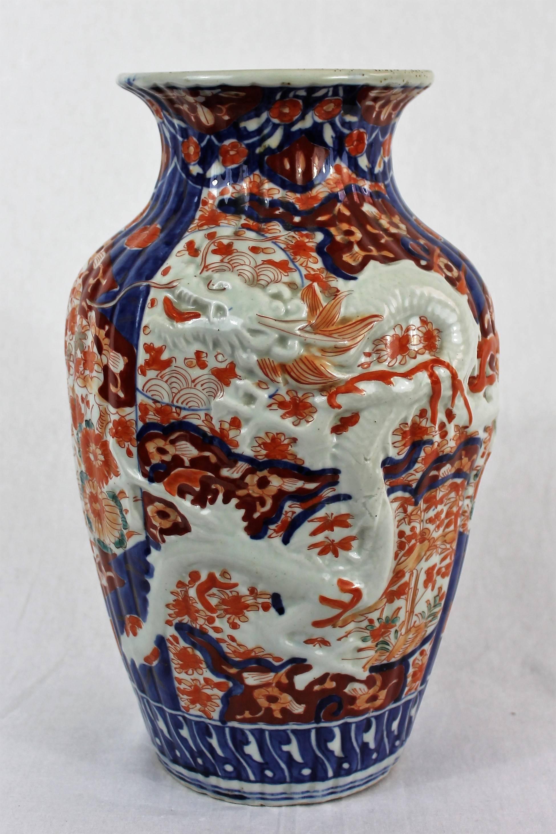 Very beautiful baluster-shaped ribbed vase in Japanese porcelain decorated with birds and flowers, in cobalt blue, iron red and white colors. Two sides of the vase are decorated with a dragon in relief. Production of the Imari area of the 19th