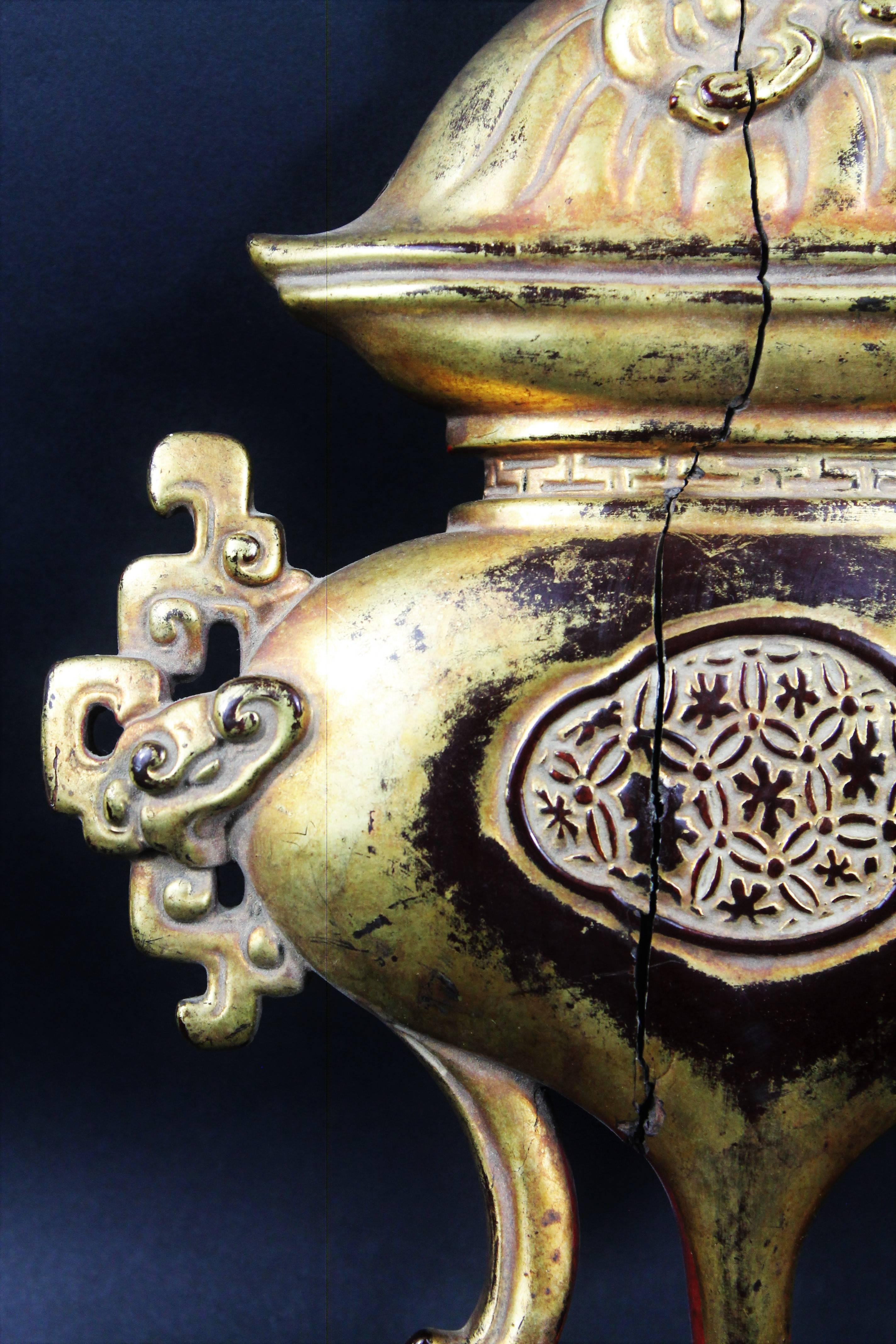 Interesting element probably coming from a lacquered and gilded wood furniture or panel representing a tripod - shaped vase with curved legs with two archaic style side handles and a shisi as a handle for the lid.
Very nice work of lacquering and