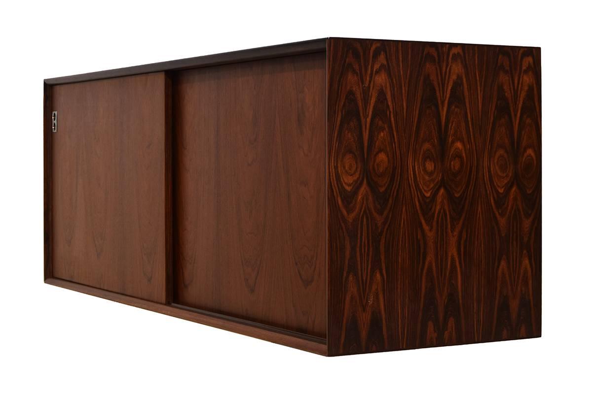 Very rare Mid-Century wall-mounted sideboard. Designed by Arne Vodder for the Danish Sibast.
The sideboard is in an excellent state. Sibast used High quality rosewood veneer and solid rosewood elements. The sideboard is 150cm wide. We have a total