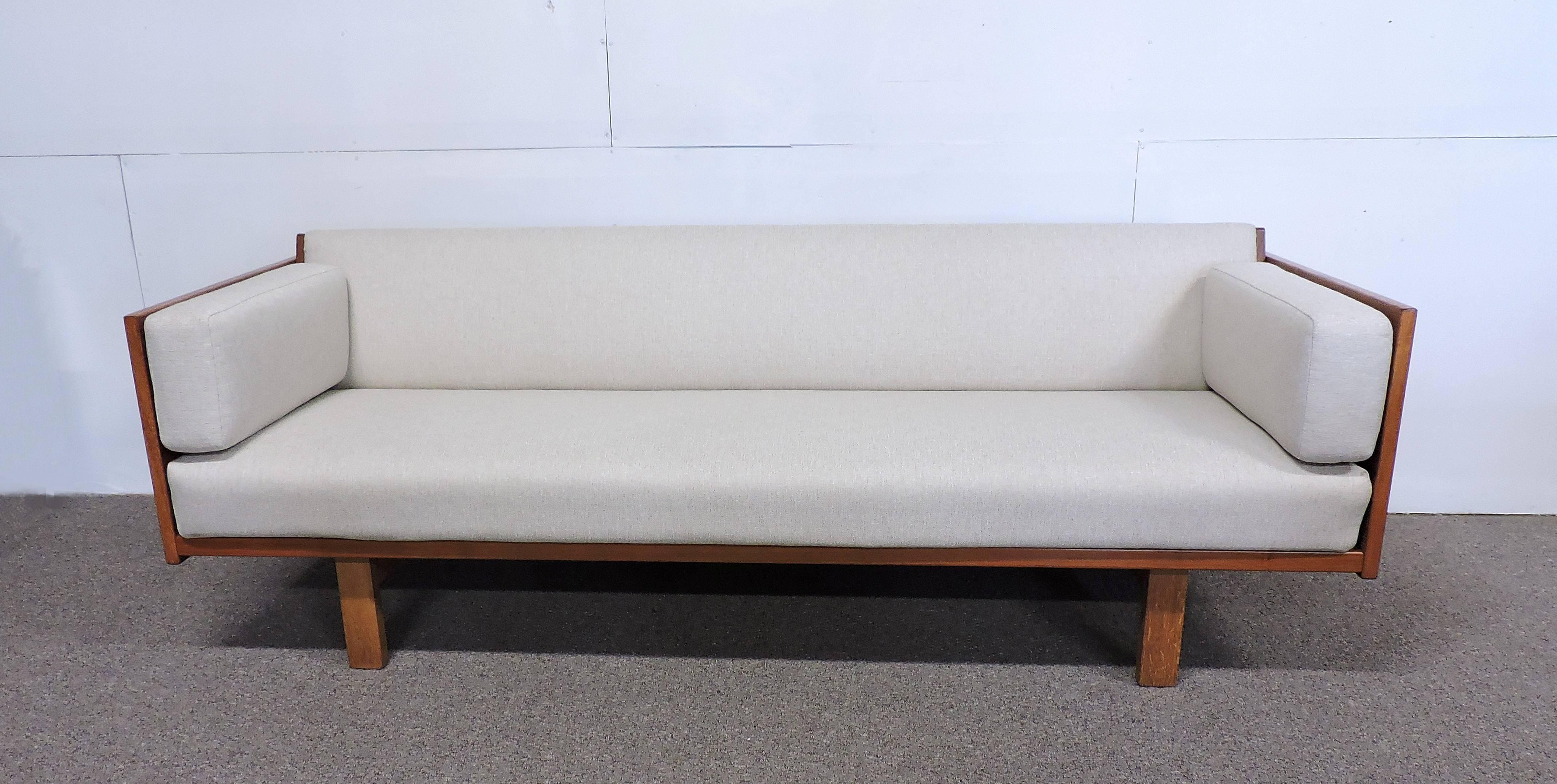Beautiful sofa or daybed designed in 1954 by Hans Wegner and manufactured in Denmark by GETAMA. This sofa has teak sides and an angled back that lifts up to make a roomy sleep area. Newly upholstered in a light beige fabric. Retains the original