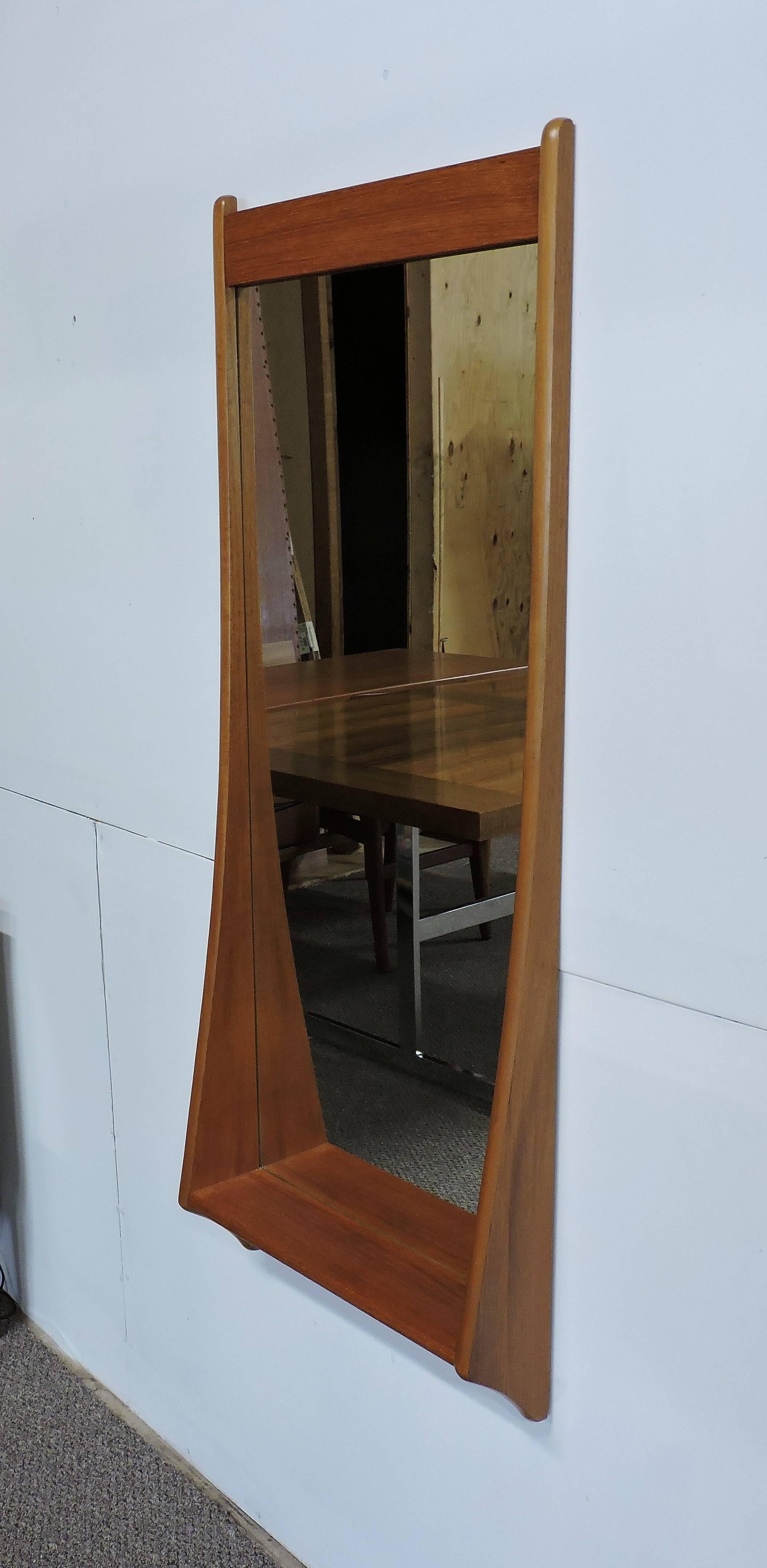 Beautiful wall mirror in teak by Pedersen and Hansen. This long mirror has sculpted and angled sides with a handy shelf on the bottom.