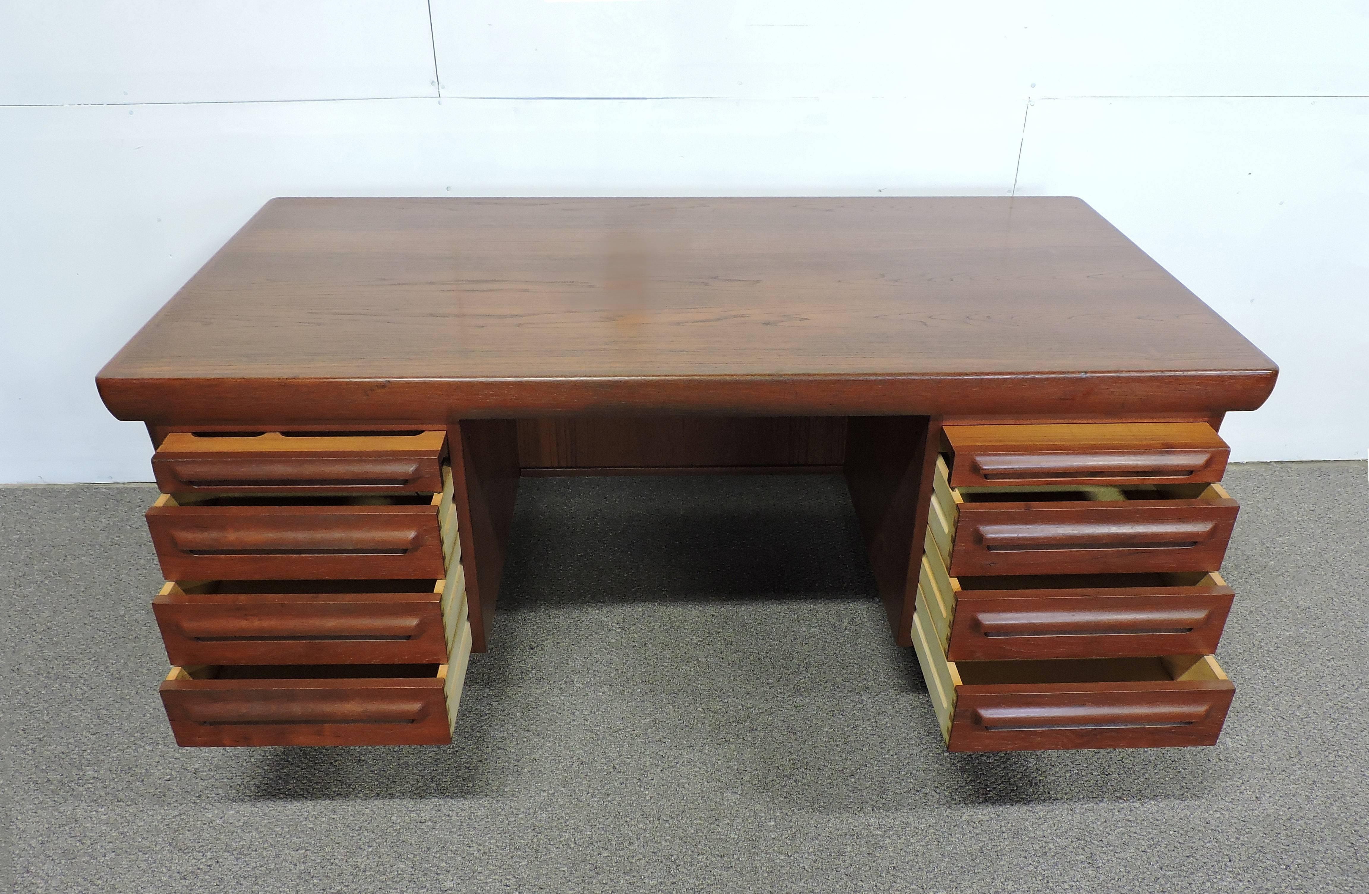 Large and impressive Danish modern teak executive desk designed by Ib Kofod Larsen and made in Denmark by Faarup Mobelfabrik. This very well crafted desk has six drawers and two pull-out trays, all with sculpted teak pulls. One of the trays has